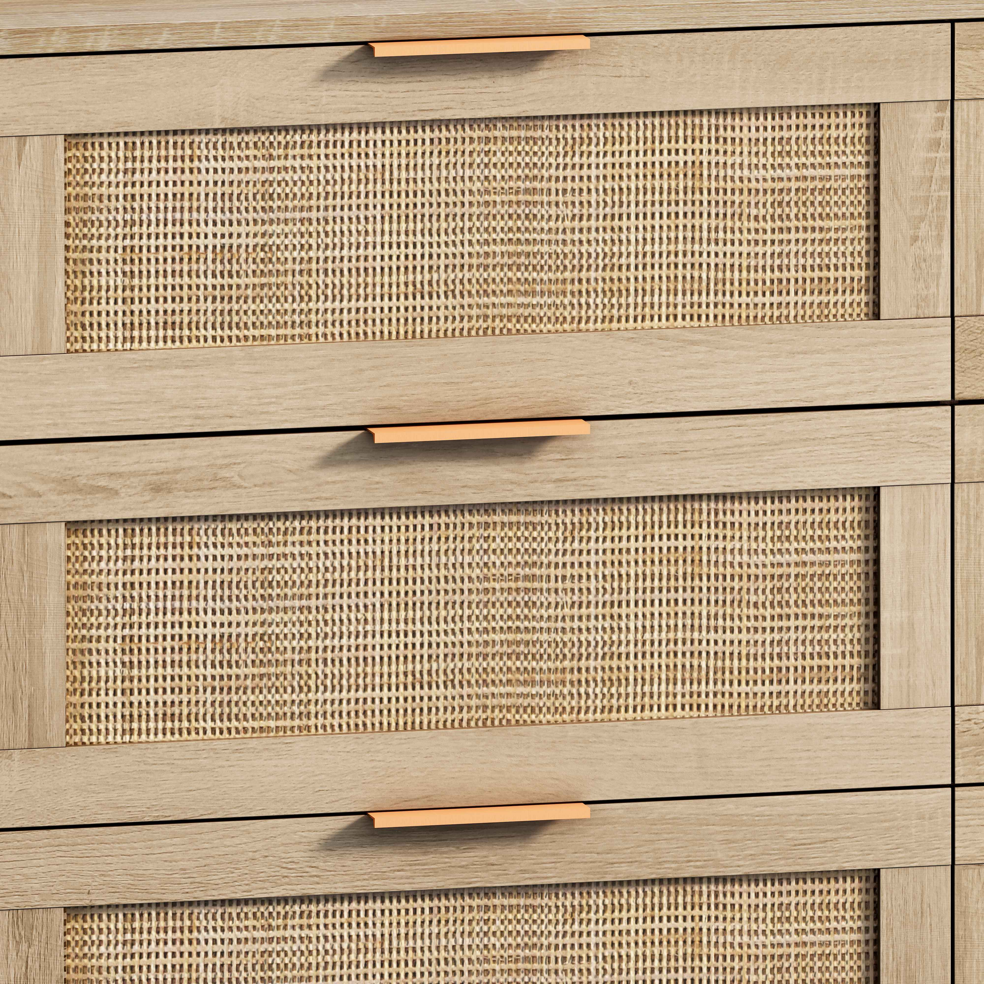Nahaufnahme eines Holzschranks mit gewebten Rattanplatten auf Schubladen und Kupfergriffen.