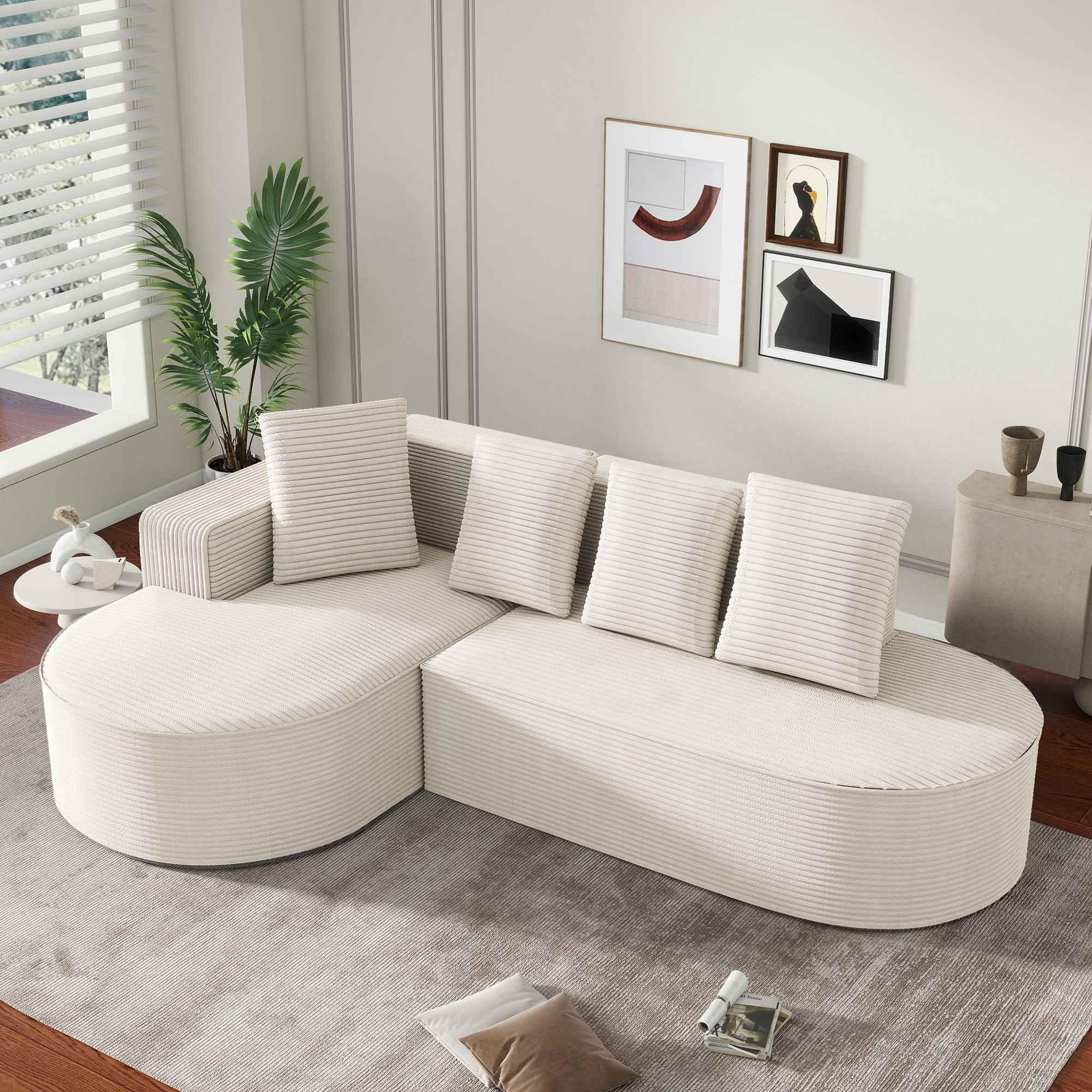 Ein cremefarbenes, geschwungenes Sofa mit Kissen in einem Raum mit Dekoration. Weißer Hintergrund.