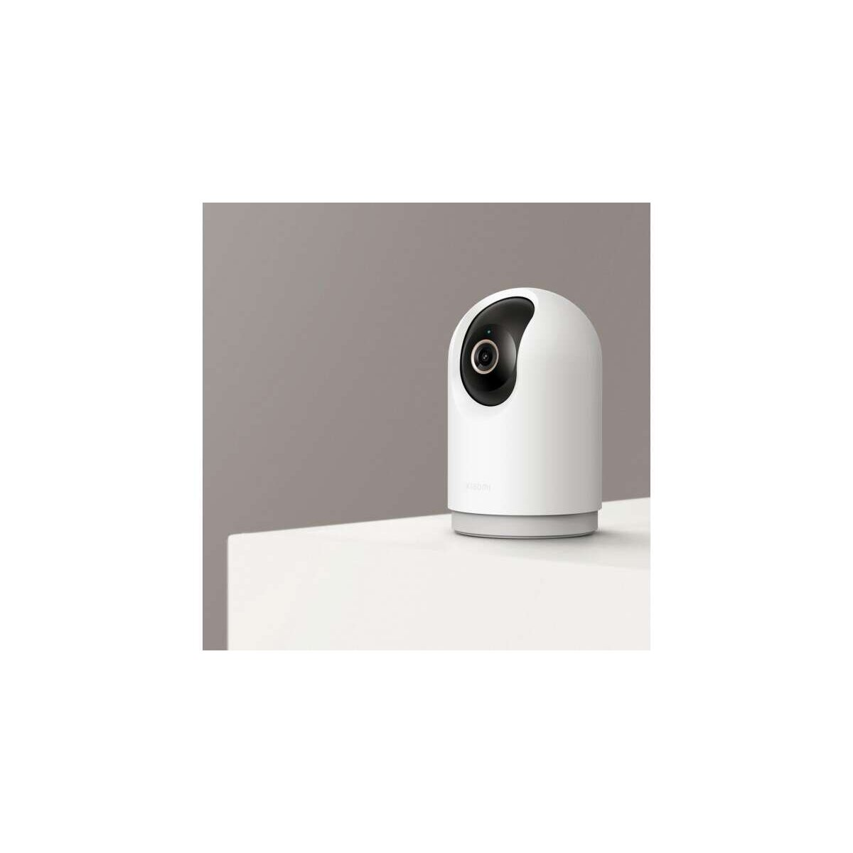 Biała kamera bezpieczeństwa na białej powierzchni, z szarym tłem. Kamera ma czarny obiektyw i szarą podstawę.