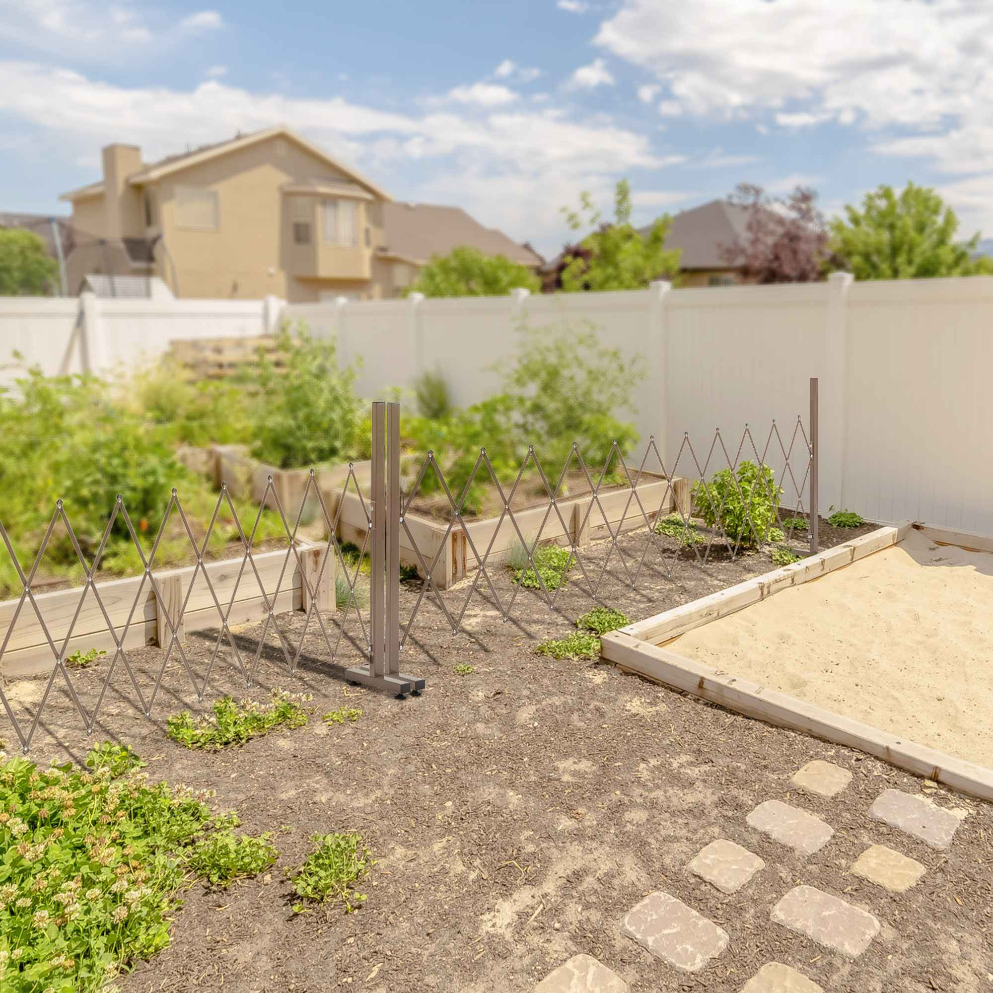 Ausziehbares braunes Tor im Garten mit Pflanzen, Sand und Haus im Hintergrund.