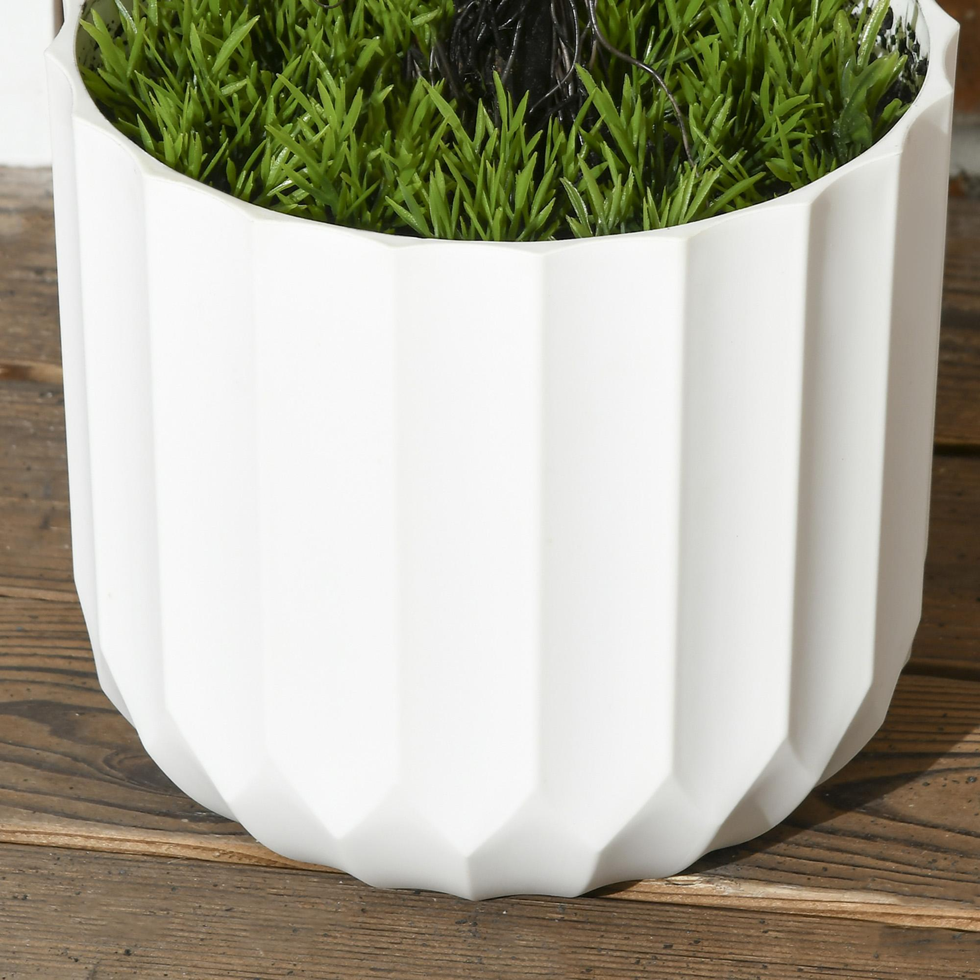 Nahaufnahme eines weißen, facettierten Topfes mit grünem Gras im Inneren. Holzoberfläche darunter.