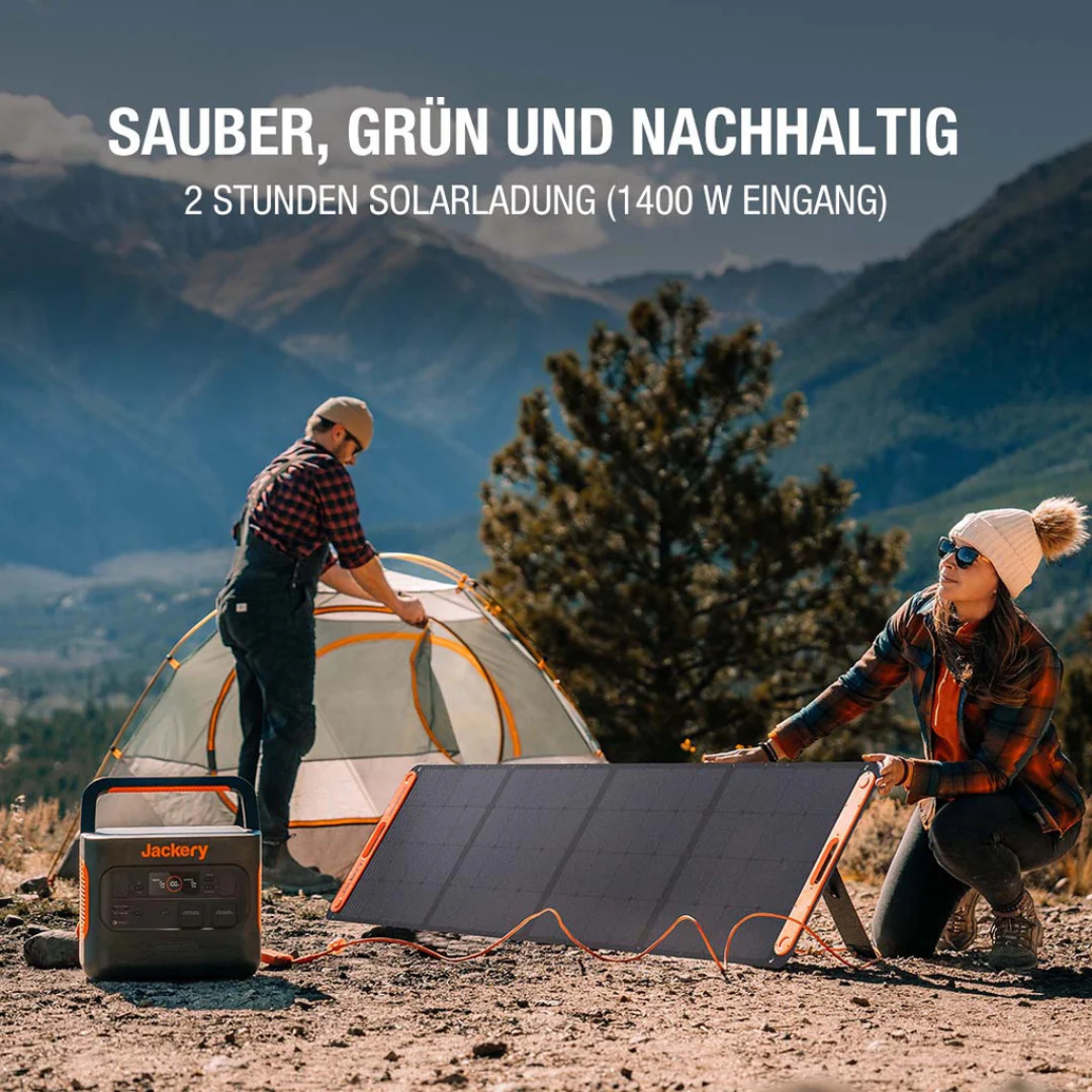 Ein Paar baut Sonnenkollektoren in der Nähe eines Zeltes auf. Eine Jackery Powerstation ist in der Nähe. Berge sind im Hintergrund.