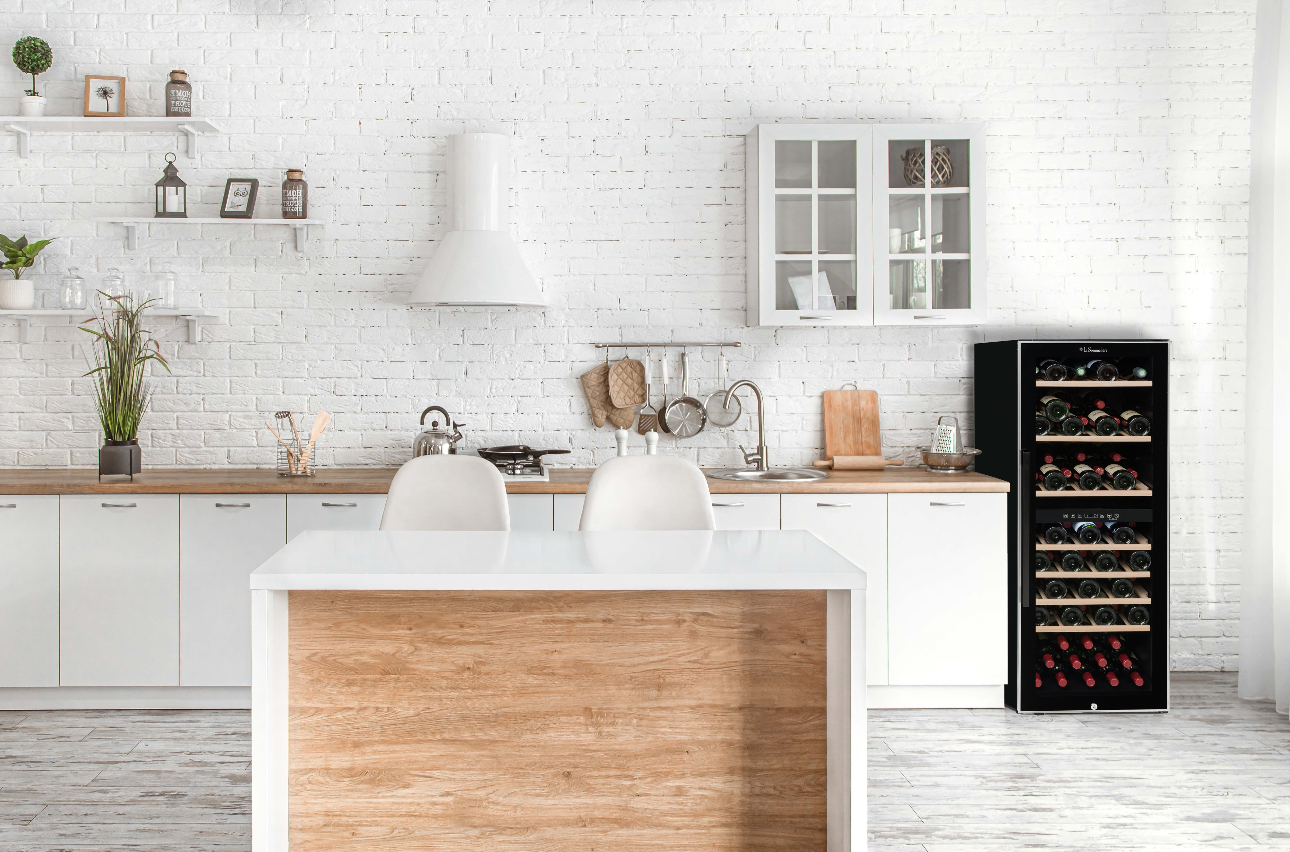 Cocina moderna con gabinetes blancos, isla y enfriador de vino.