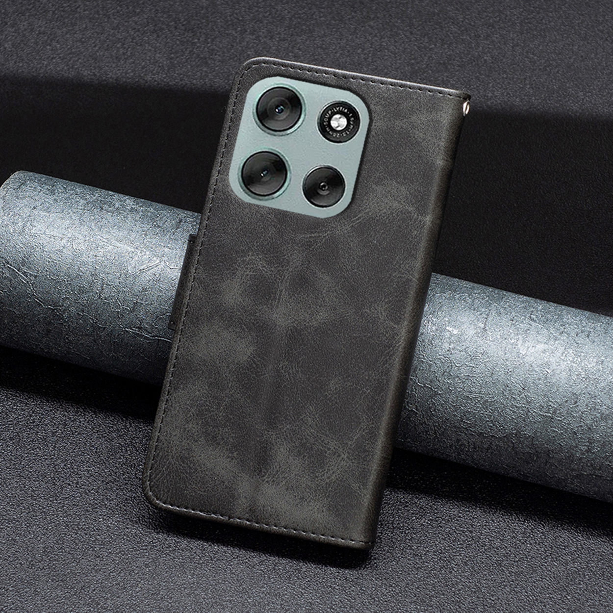 Een donkergrijze telefoonhoes met vier cameralenzen. De hoes is open, toont een leerachtige textuur en ligt op een grijze ondergrond.
