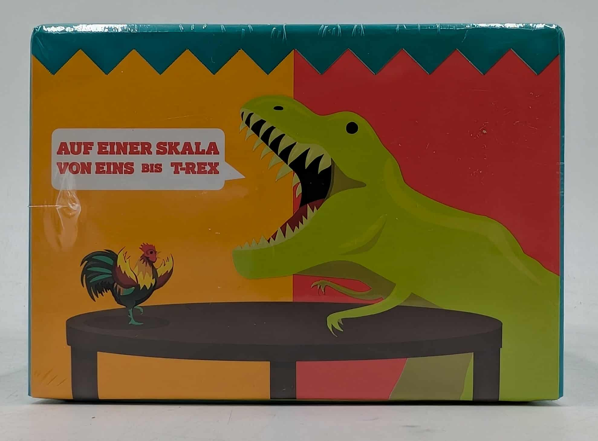 Spielbox mit T-Rex und Hahn. Text: 'Auf einer Skala von Eins bis T-Rex'.