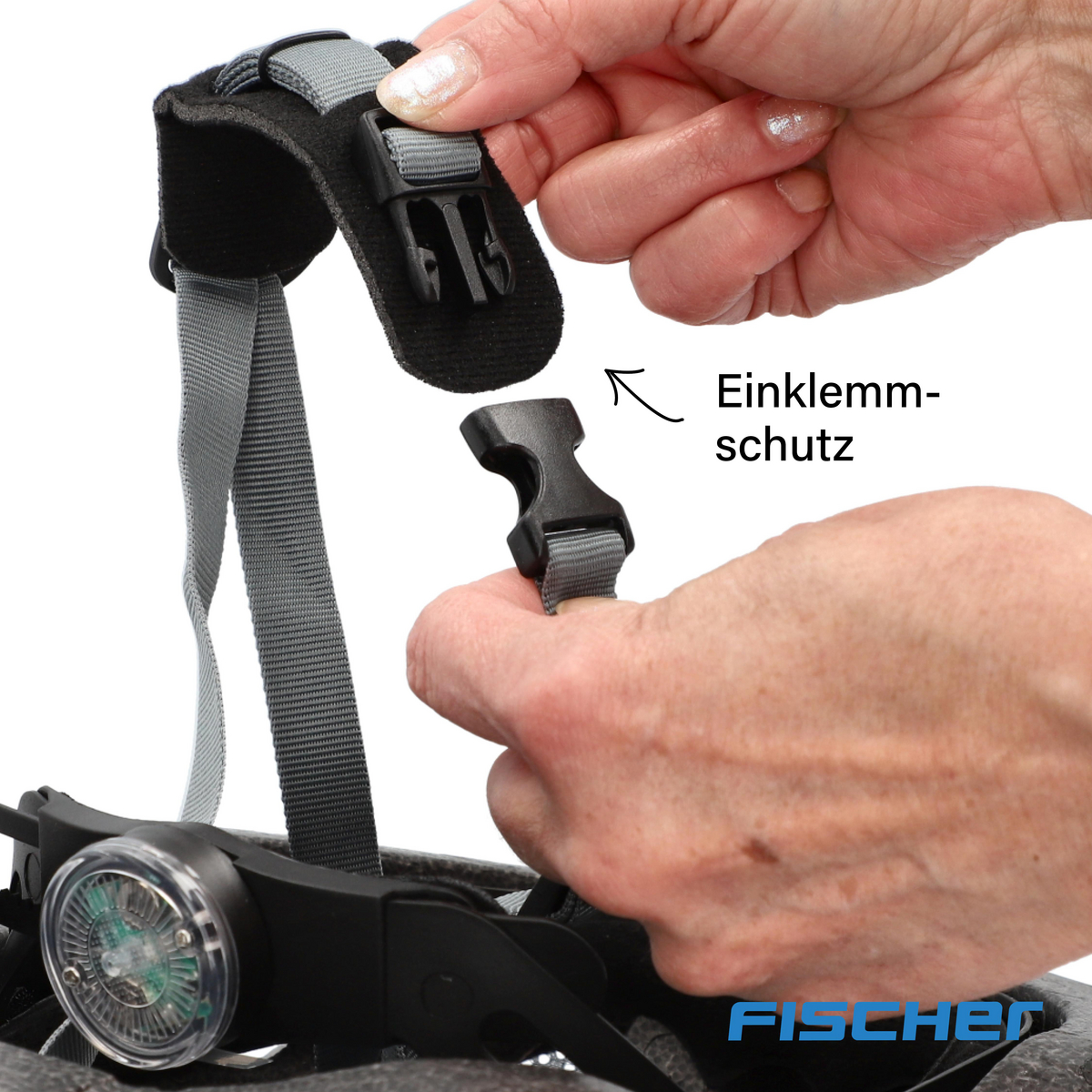 Hände, die den Riemen eines schwarzen Fahrradhelms einstellen. Der Text 'Einklemmschutz' ist sichtbar.