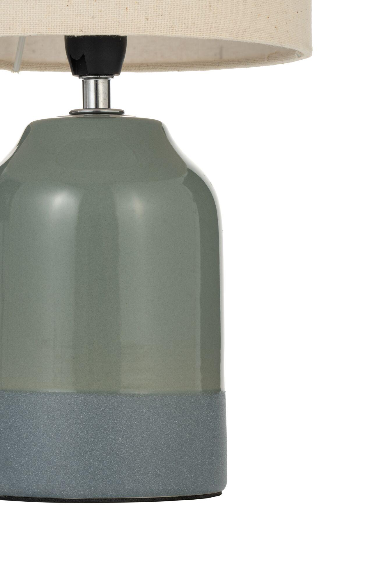 Lampa z jasnozielono-niebieską podstawą i kremowym kloszem. Stoi na białej powierzchni.