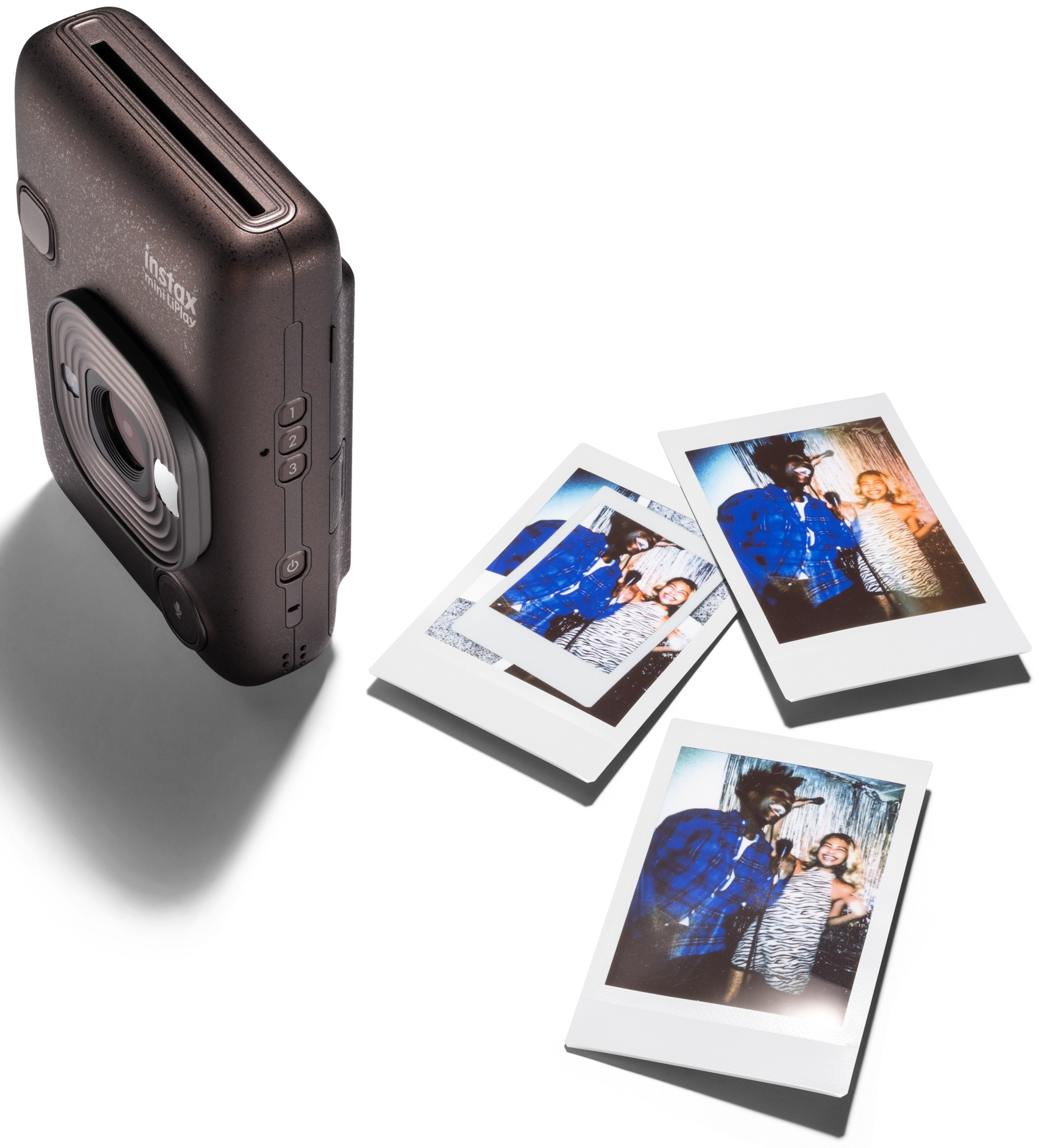 Aparat natychmiastowy i zdjęcia. Aparat jest ciemnobrązowy, a zdjęcia pokazują pozujących ludzi.