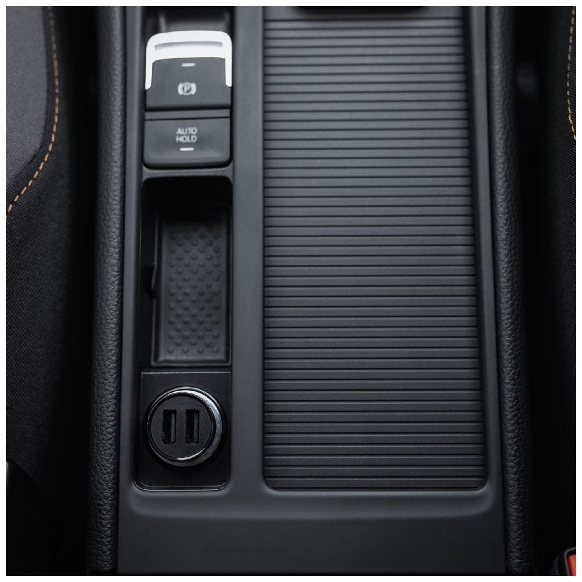 Autointerieur mit schwarzer Konsole, Knöpfen und USB-Anschlüssen. Der Fokus liegt auf Funktionalität.