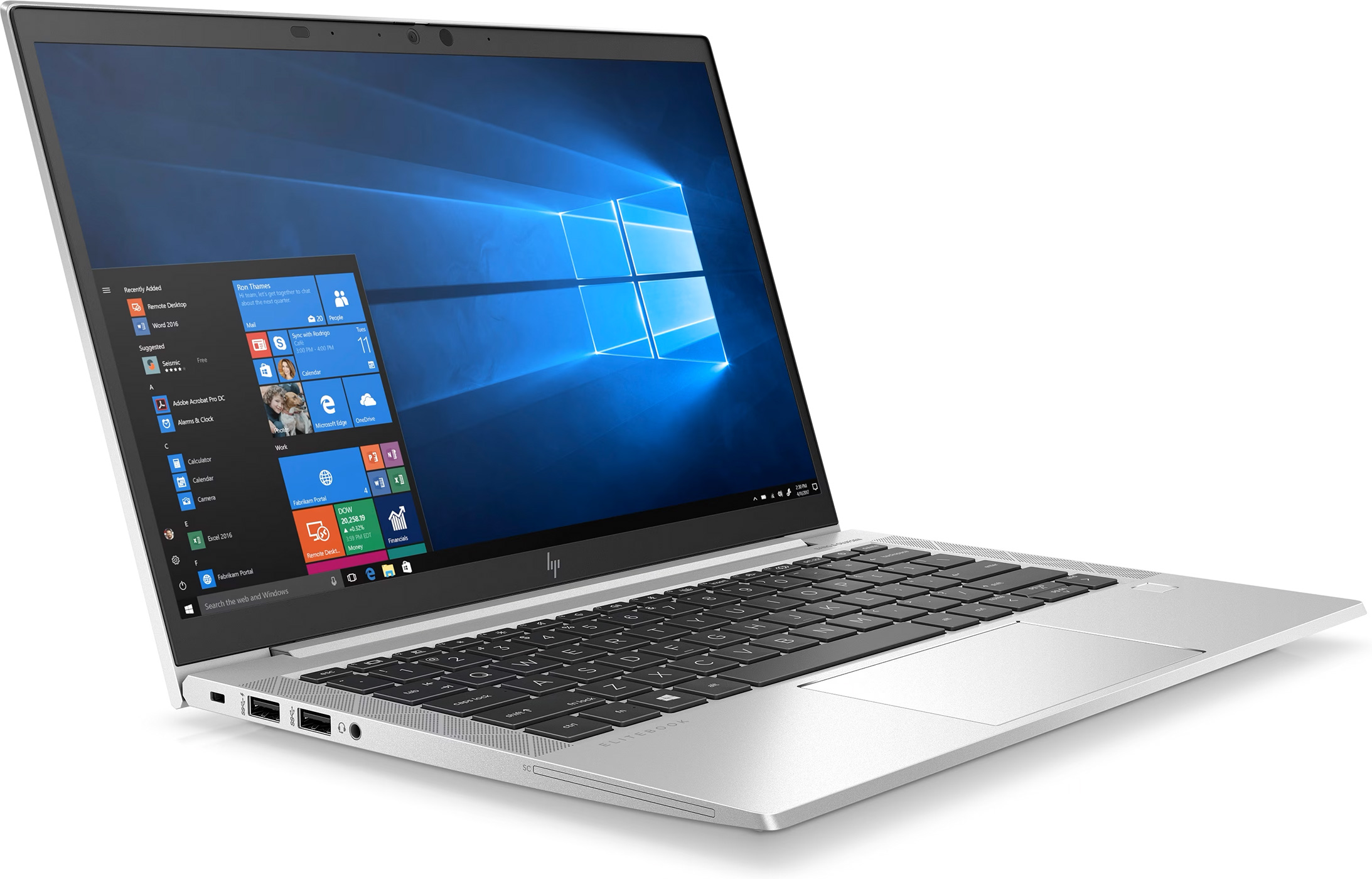 A silver laptop on a white surface, open with a lit screen showing a Windows interface.