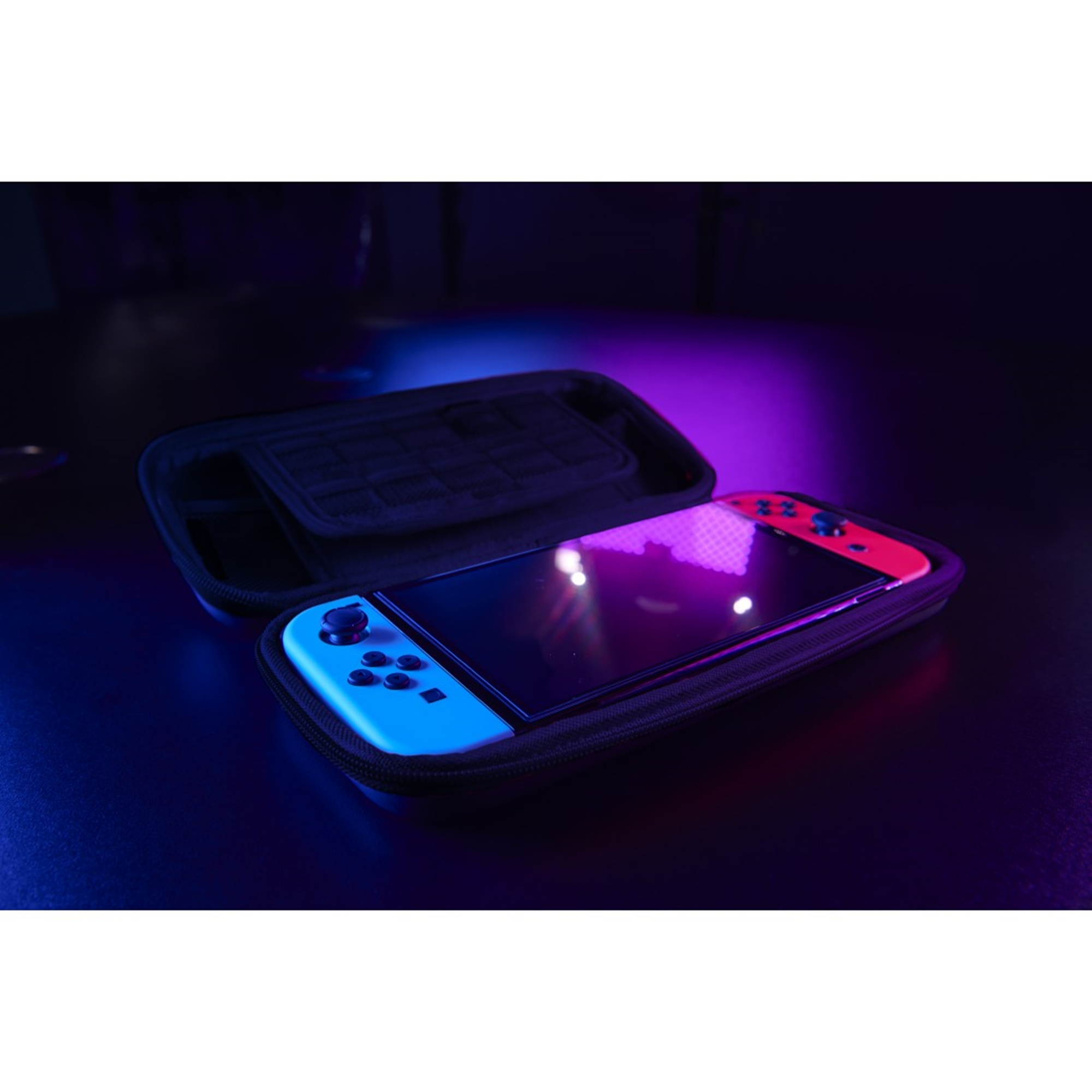 Nintendo Switch in einem Koffer, mit blauen und roten Controllern, unter Neonlicht.