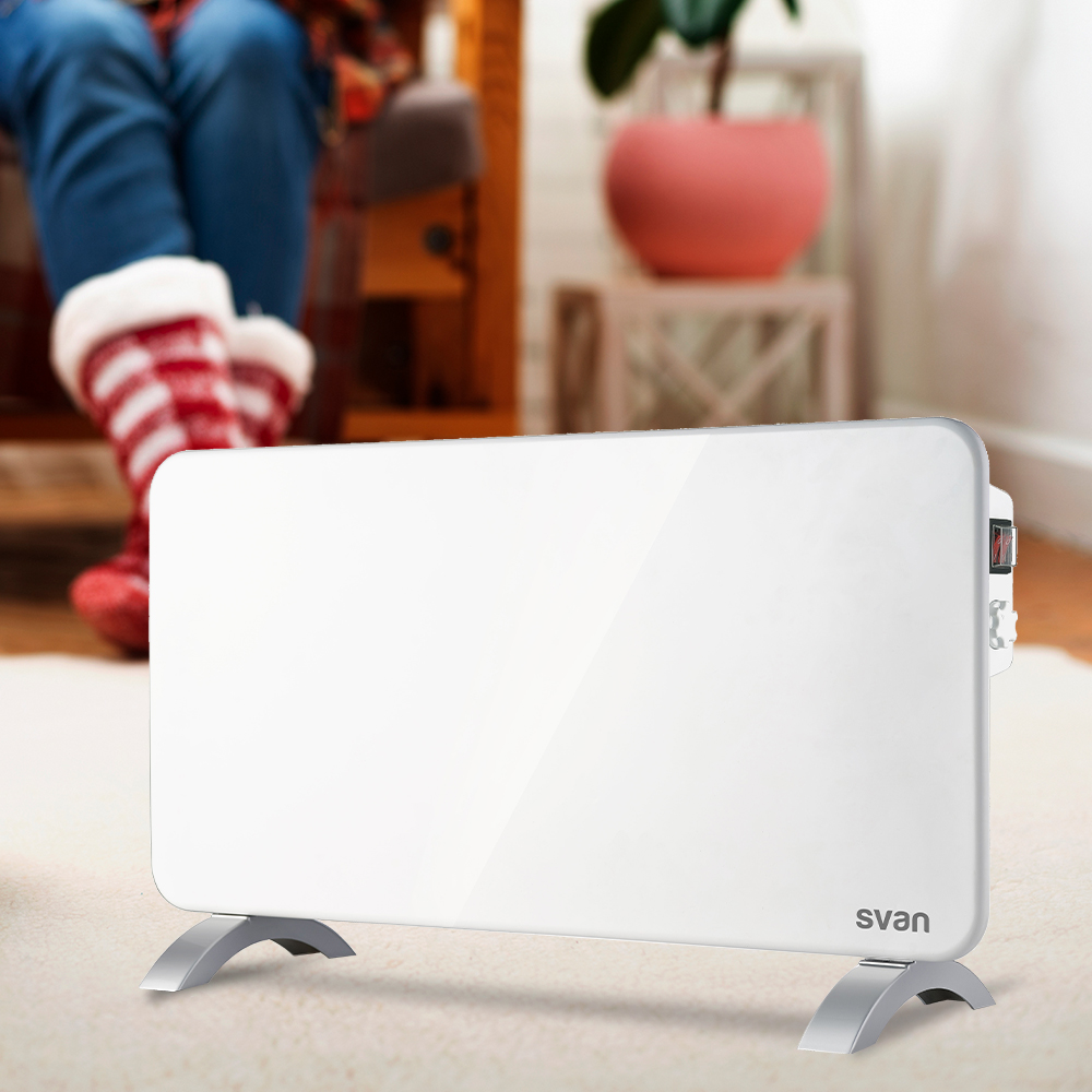 Un calefactor eléctrico blanco en el suelo. Persona en el fondo con calcetines rojos y blancos.