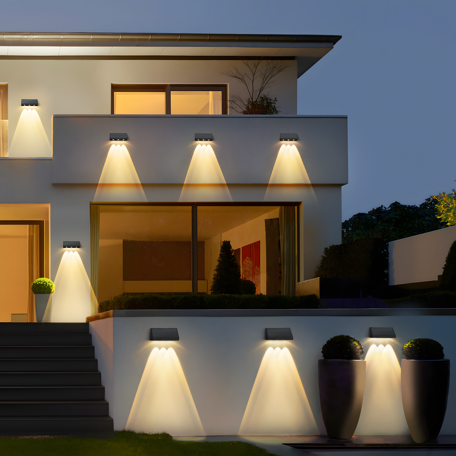 Widok zewnętrzny domu w nocy, z wieloma lampami solarnymi oświetlającymi ściany i schody.