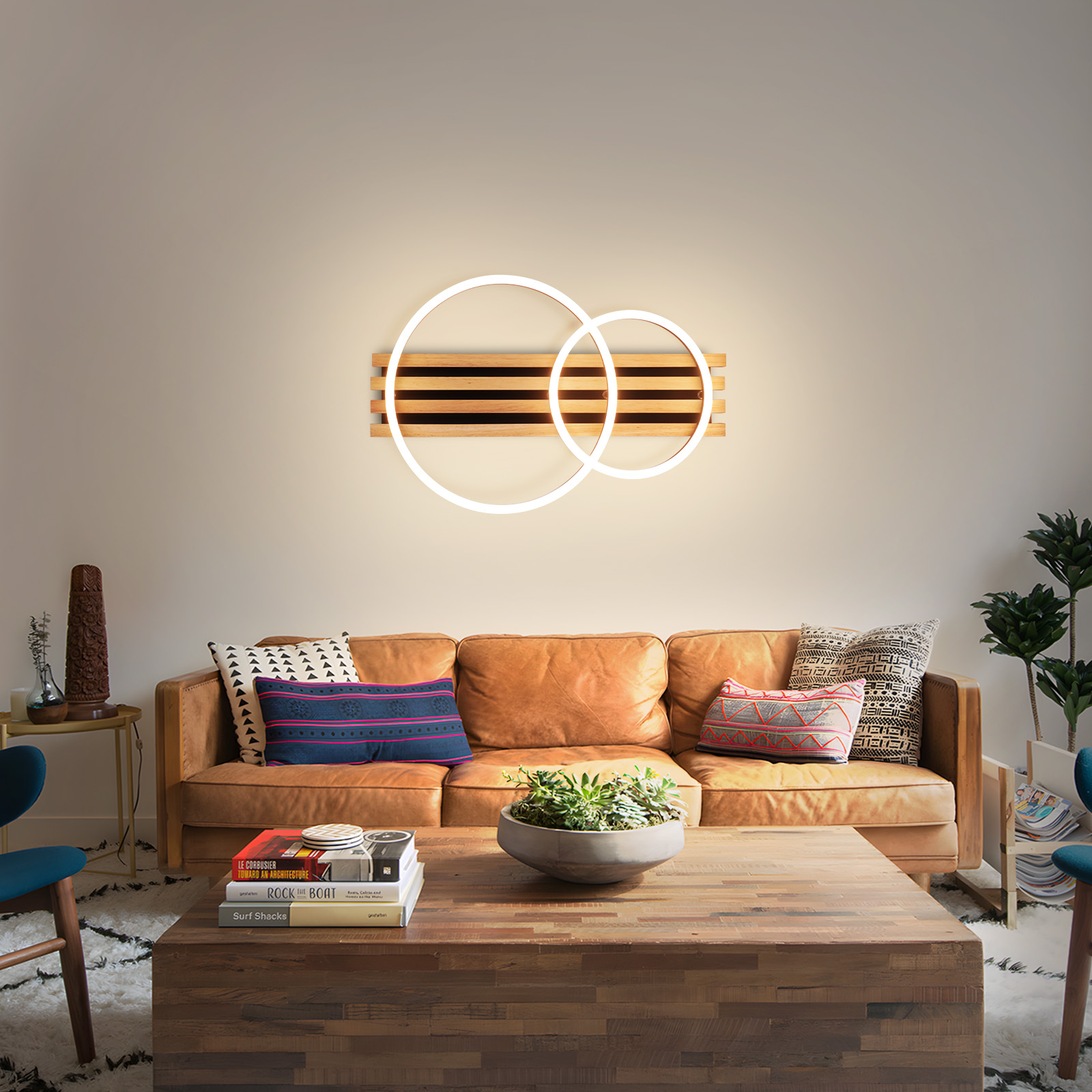 Wohnzimmer mit braunem Sofa, Holztisch und Wandleuchte. Die Leuchte ist rechteckig.