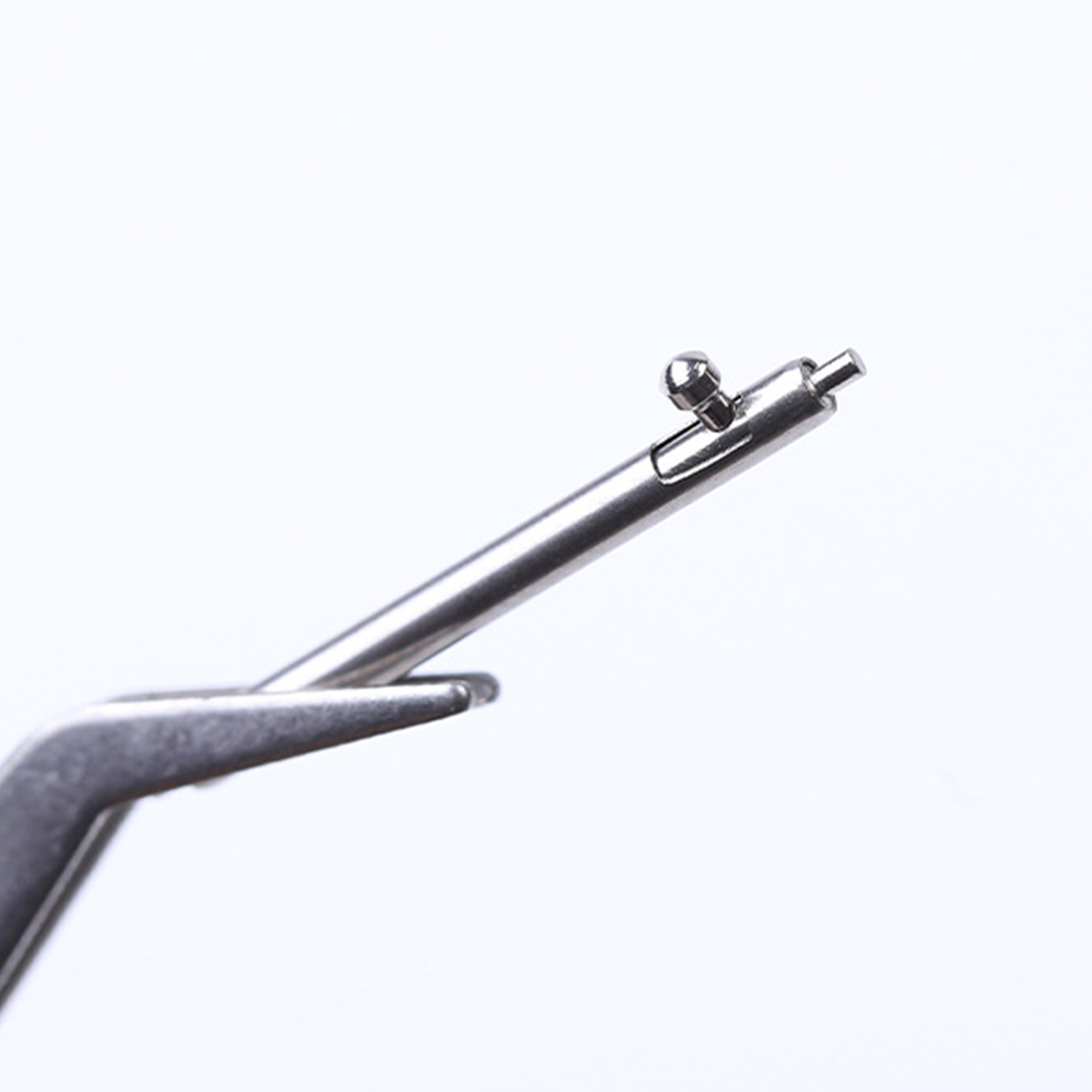 Pręt sprężynowy do zegarka i narzędzie, ujęcie z bliska. Srebrny pręt sprężynowy z małym pokrętłem zwalniającym i narzędziem.