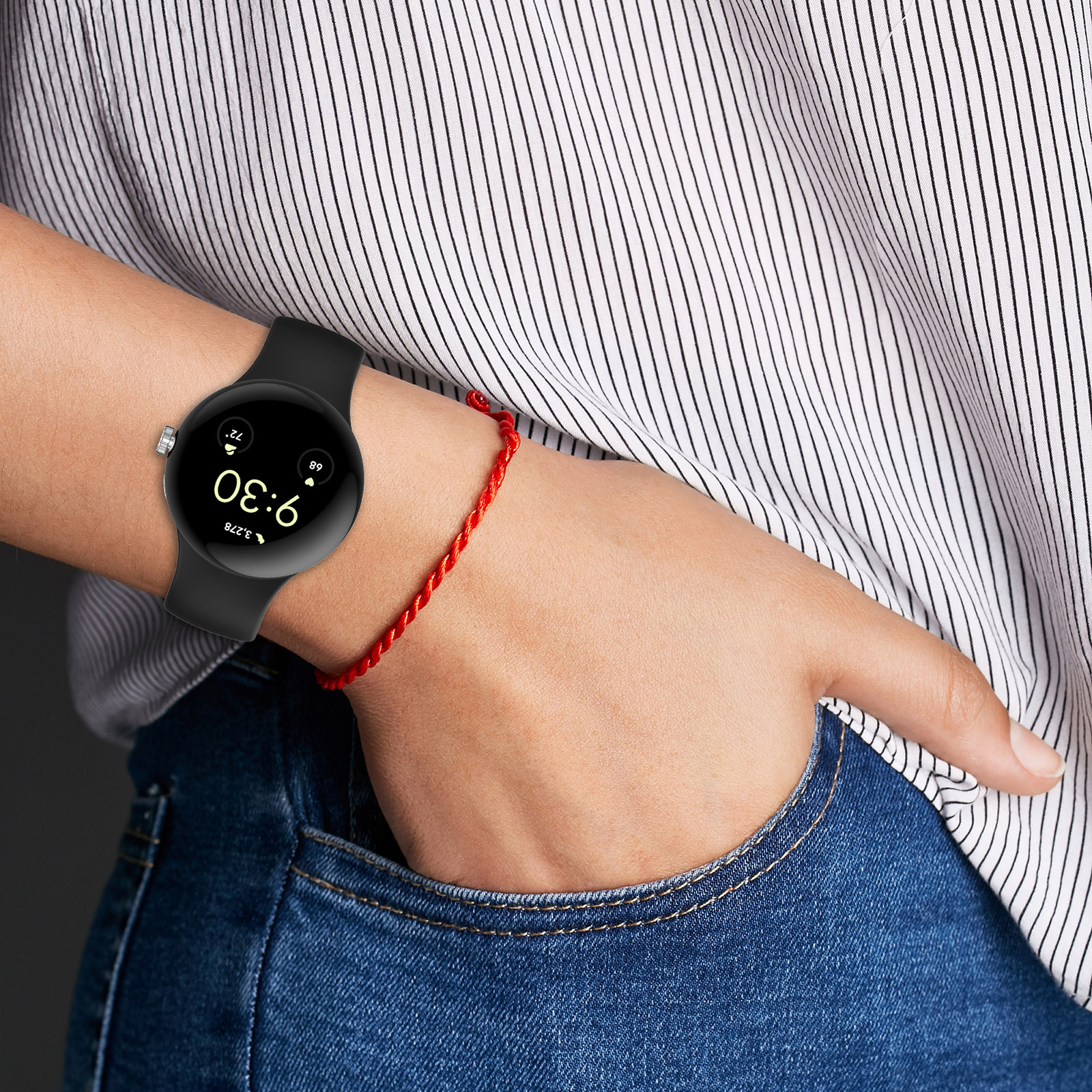 Handgelenk mit schwarzer Smartwatch, die Zeit und Statistiken anzeigt. Ein rotes Armband ist auch am Handgelenk.