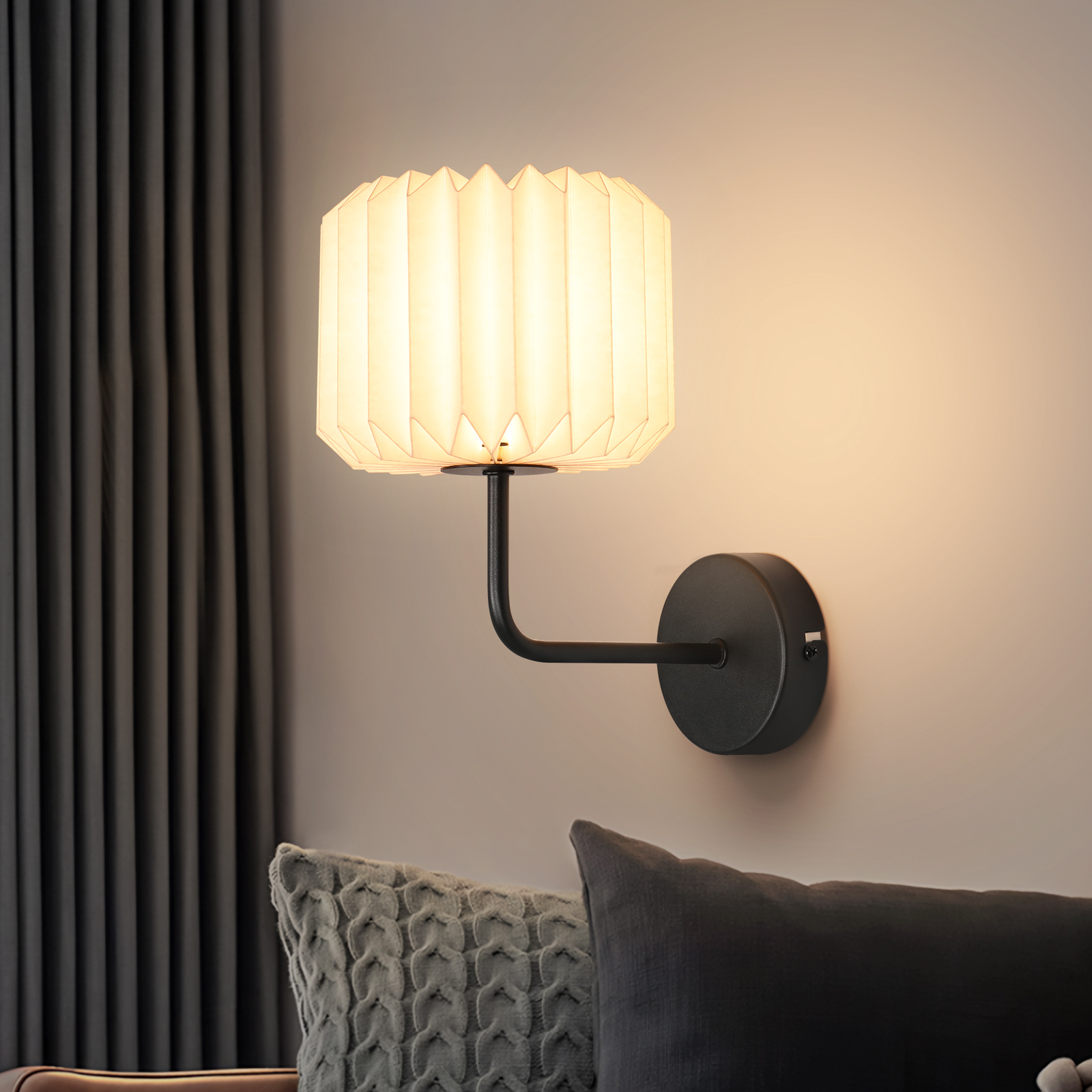 Lampa ścienna z plisowanym abażurem. Lampa jest na jasnoróżowej ścianie, tworząc przytulną atmosferę.