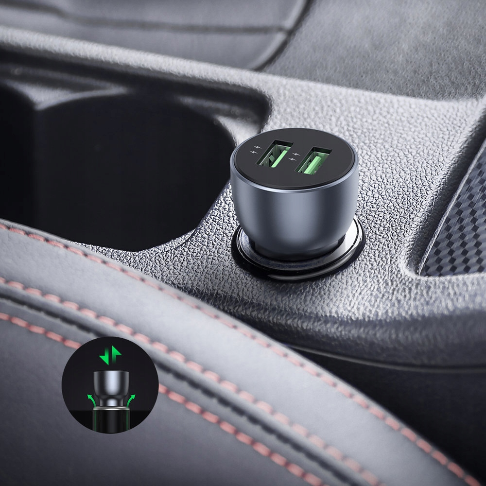 Ciemnoszara ładowarka samochodowa UGREEN w konsoli środkowej samochodu. Zielone światła wskazują ładowanie. Ładowarka ma dwa porty.