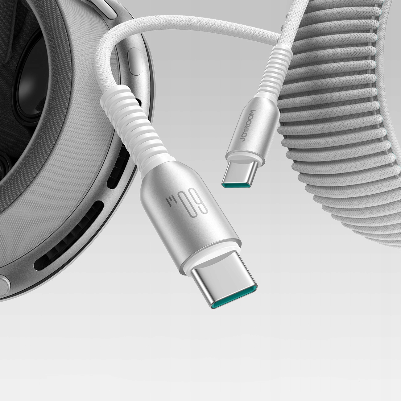 Biały kabel USB-C ze srebrnymi złączami. Kabel jest zwinięty i podłączony do białych słuchawek.
