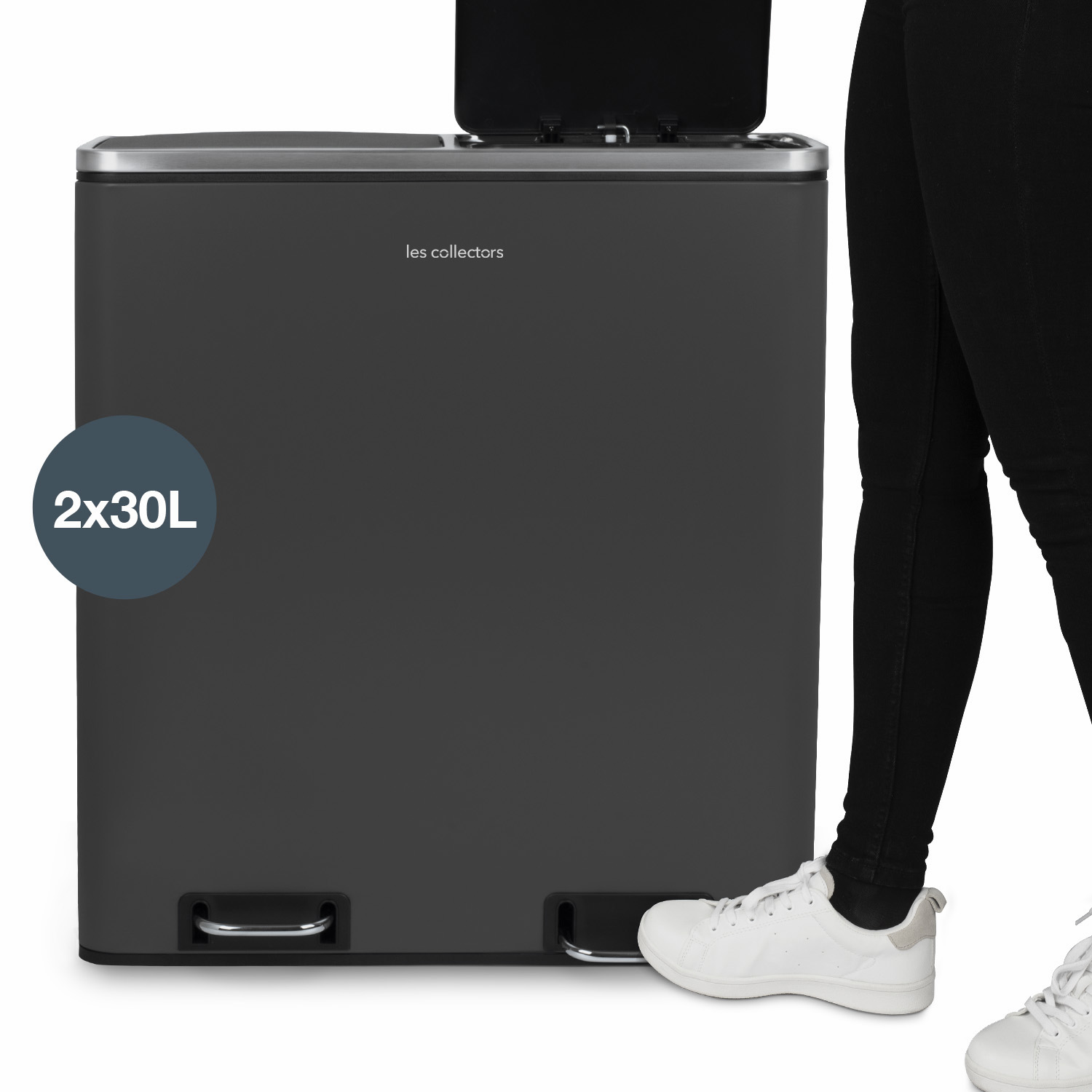 Eine Person steht neben einem dunkelgrauen Mülleimer. Er hat ein Dual-Compartment-Design, wobei der Deckel offen ist.