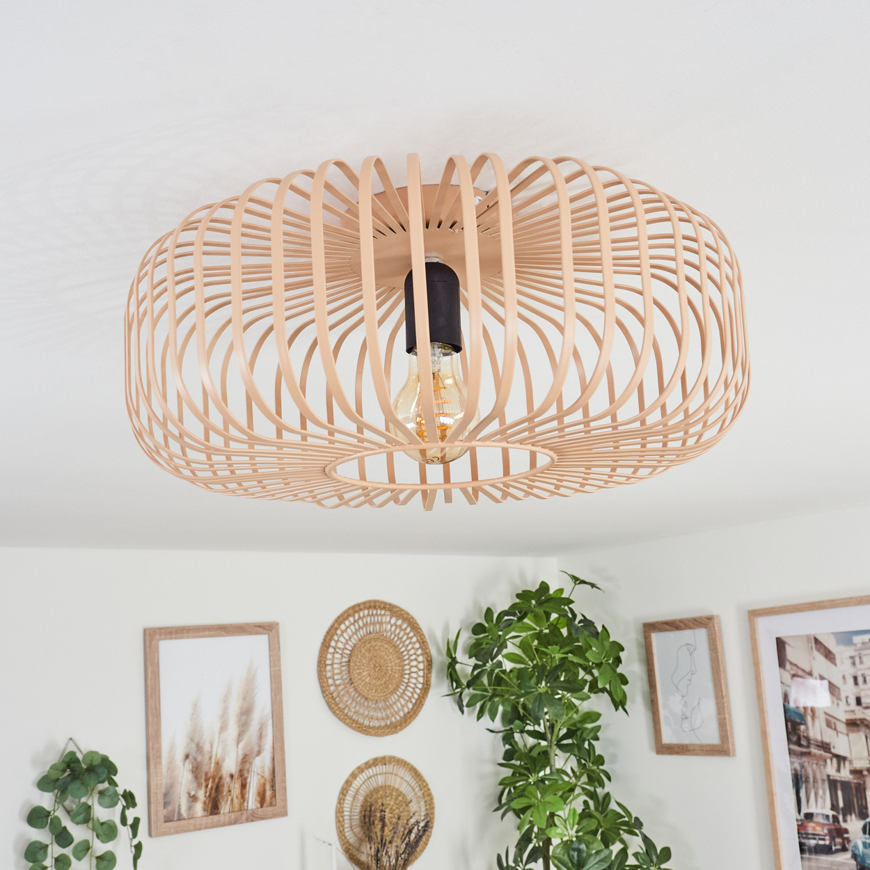 Eine helle Deckenlampe aus Holz mit rundem, käfigartigem Design ist an einer weißen Decke montiert. Darunter befinden sich mehrere Dekorationen.
