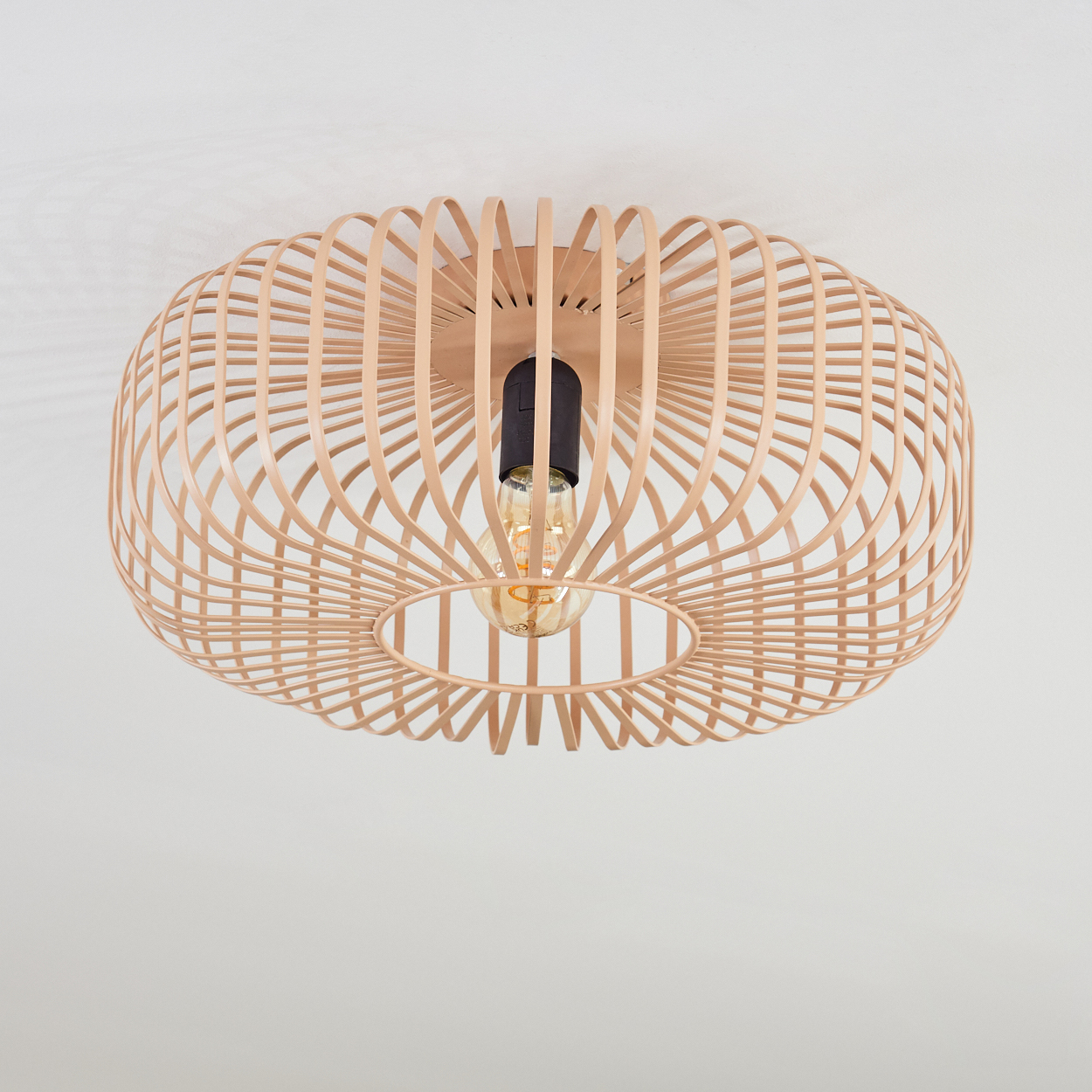 Deckenlampe mit Glühbirne und einem hölzernen, gewebten Schirm. Die Lampe hängt vor einer weißen Decke.