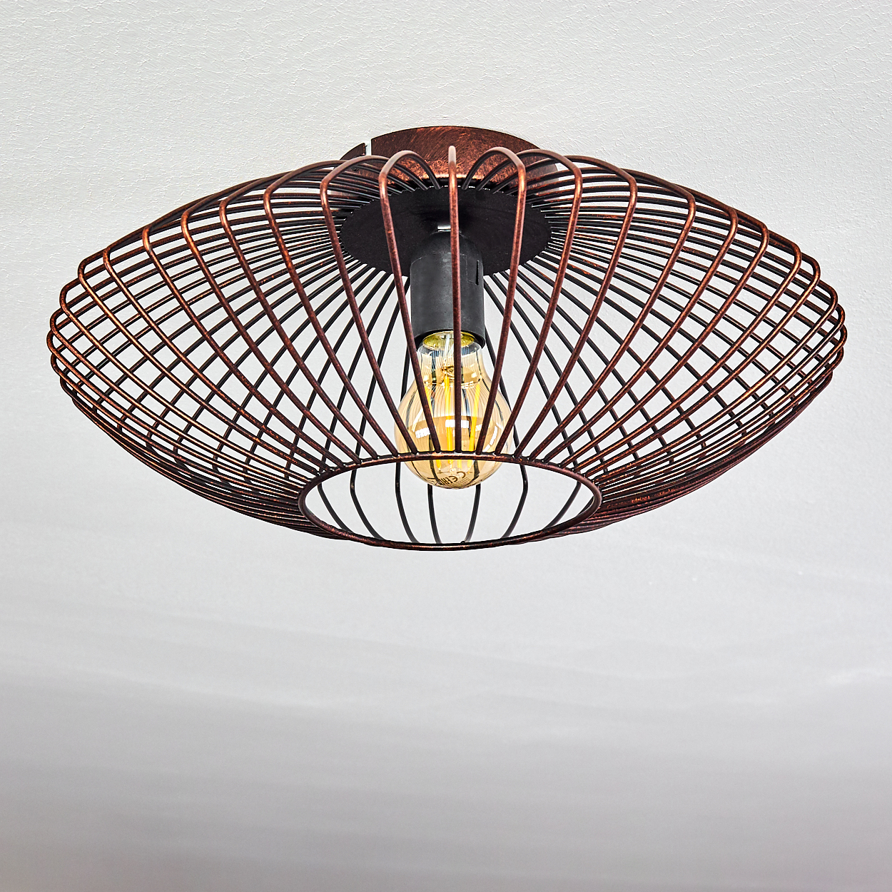 Deckenlampe mit kupferfarbenem Drahtrahmen-Design und Glühbirne. Sie hängt an einer weißen Decke.
