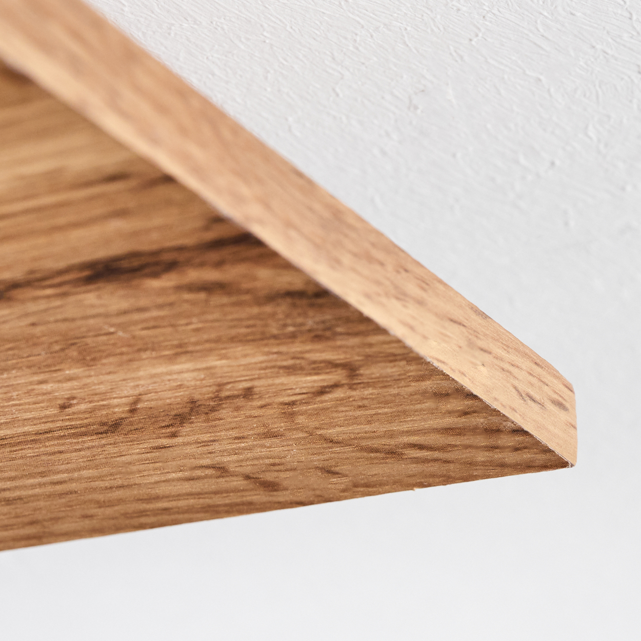 Nahaufnahme der Kante einer Holzplatte. Die Holzmaserung ist sichtbar, und die Oberfläche ist glatt und sauber.