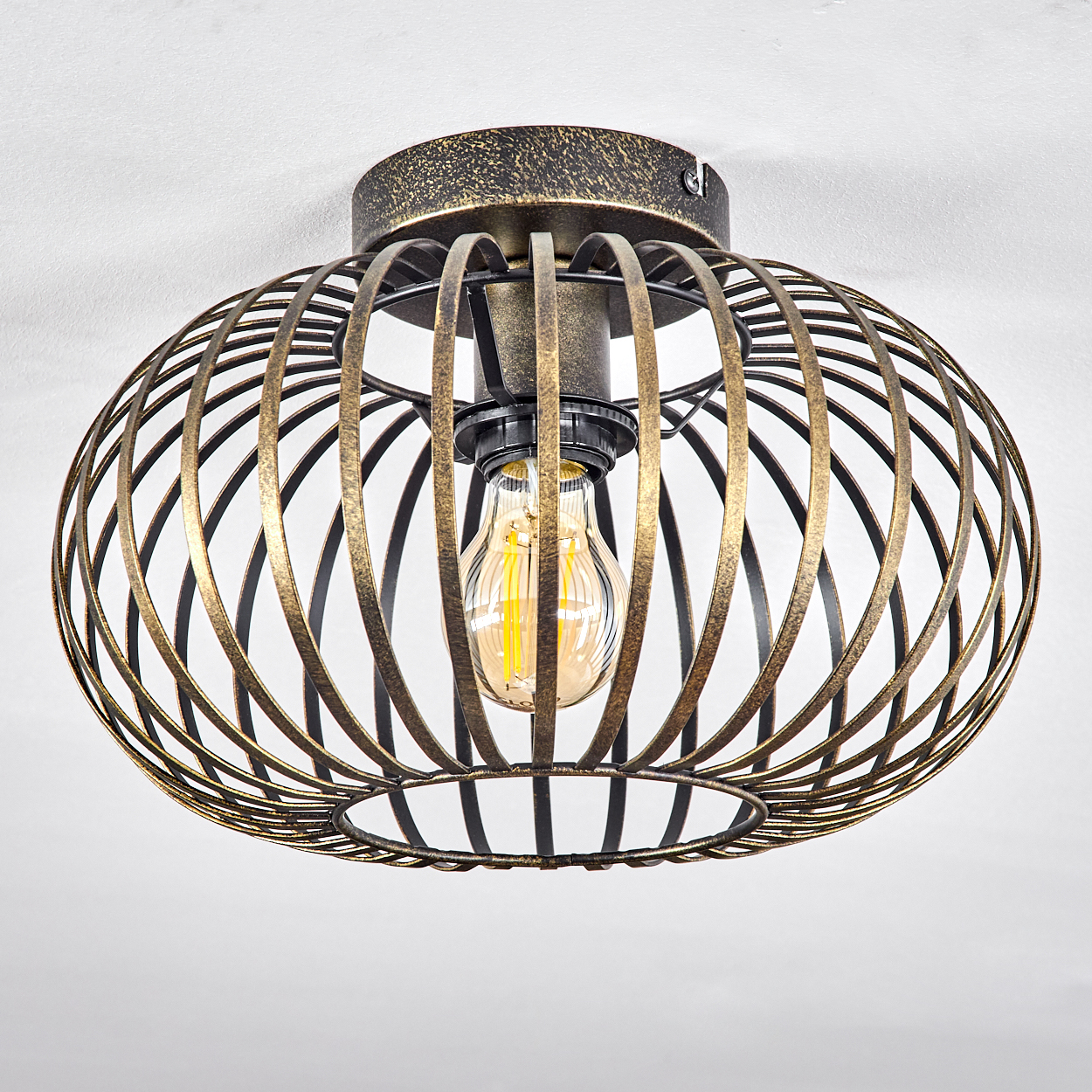 Eine Deckenlampe mit Käfigdesign und sichtbarer Glühbirne. Die Lampe ist gold und dunkel.