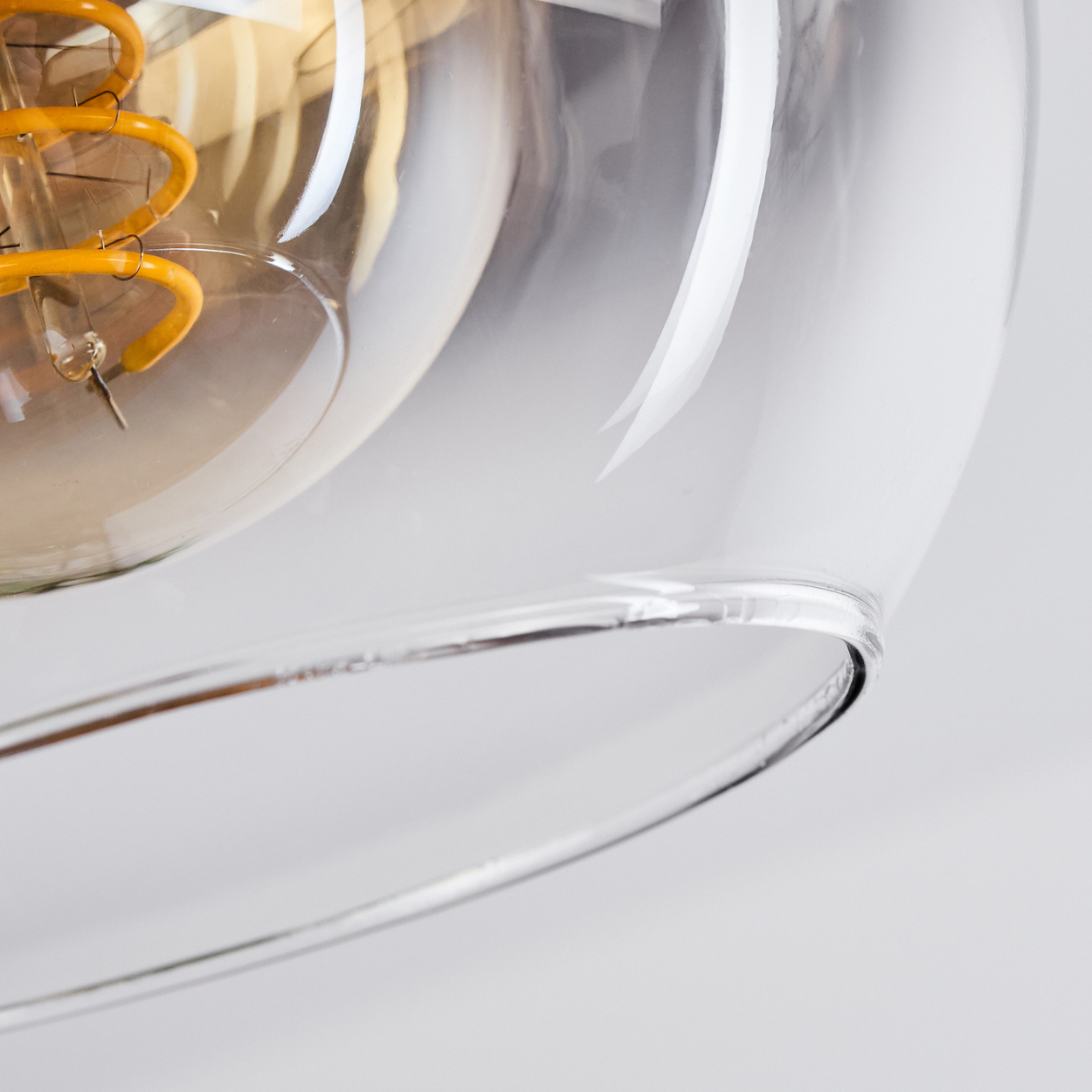 Nahaufnahme einer Glühbirne mit gelbem Glühfaden in einem Glasschirm. Weißer Hintergrund.