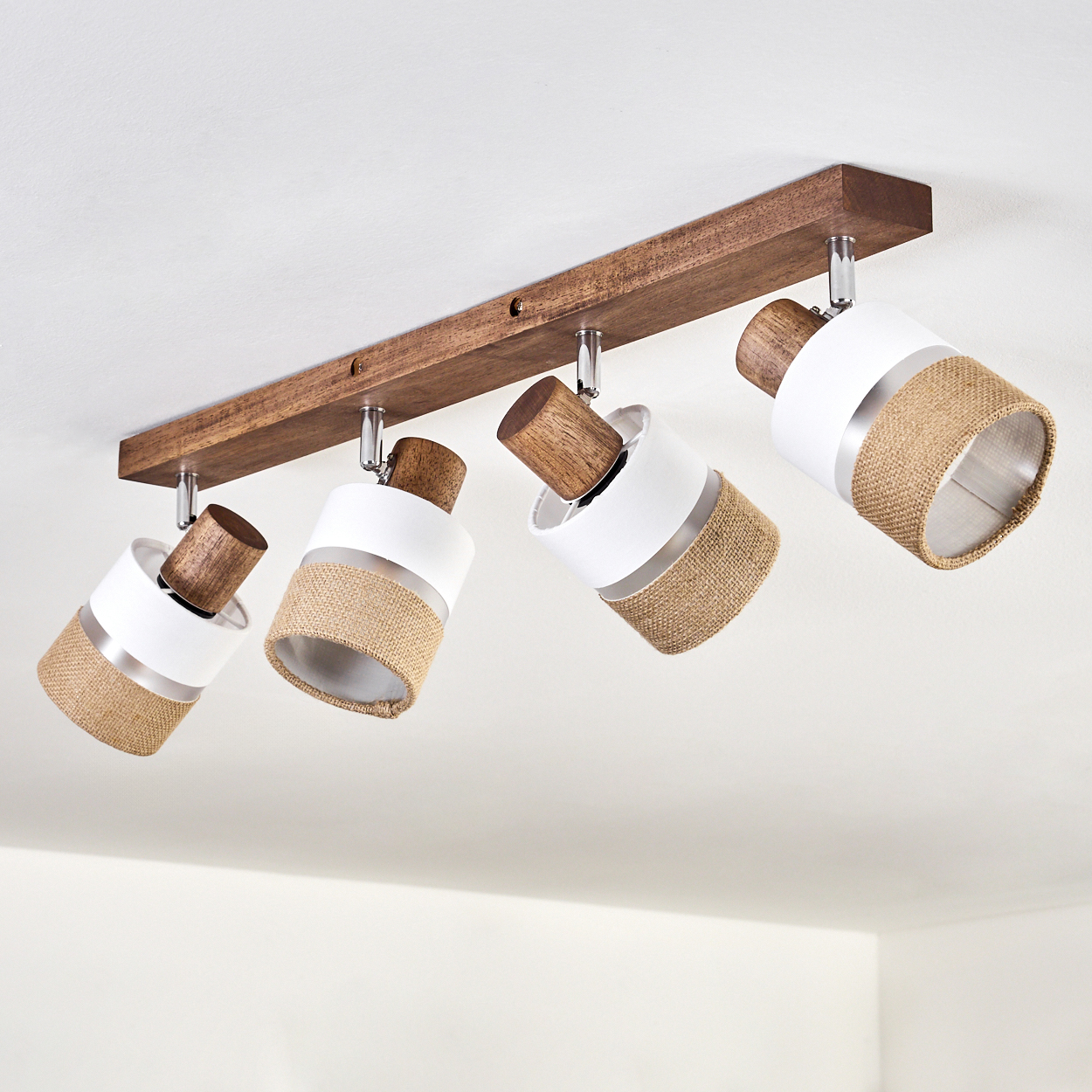 Deckenleuchte mit vier Strahlern. Die Lampen haben weiße und Jute-Schirme mit Holzakzenten.