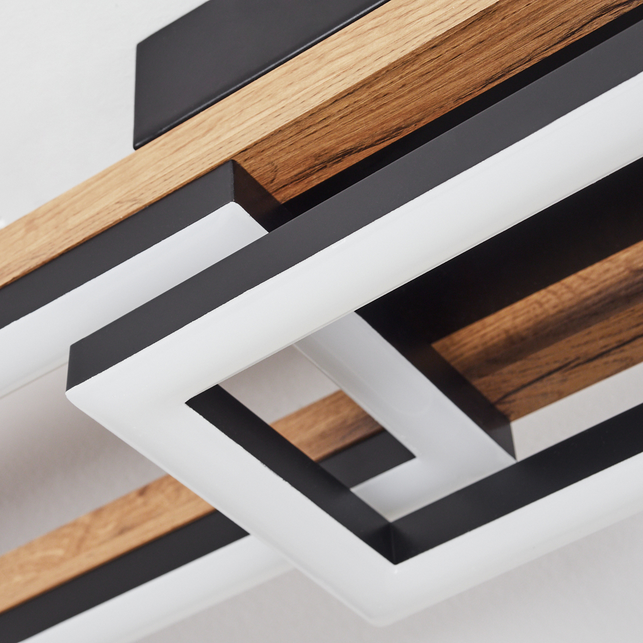 Nahaufnahme einer modernen Deckenlampe mit Holzsockel und geometrischen Schwarz-Weiß-Leuchten.
