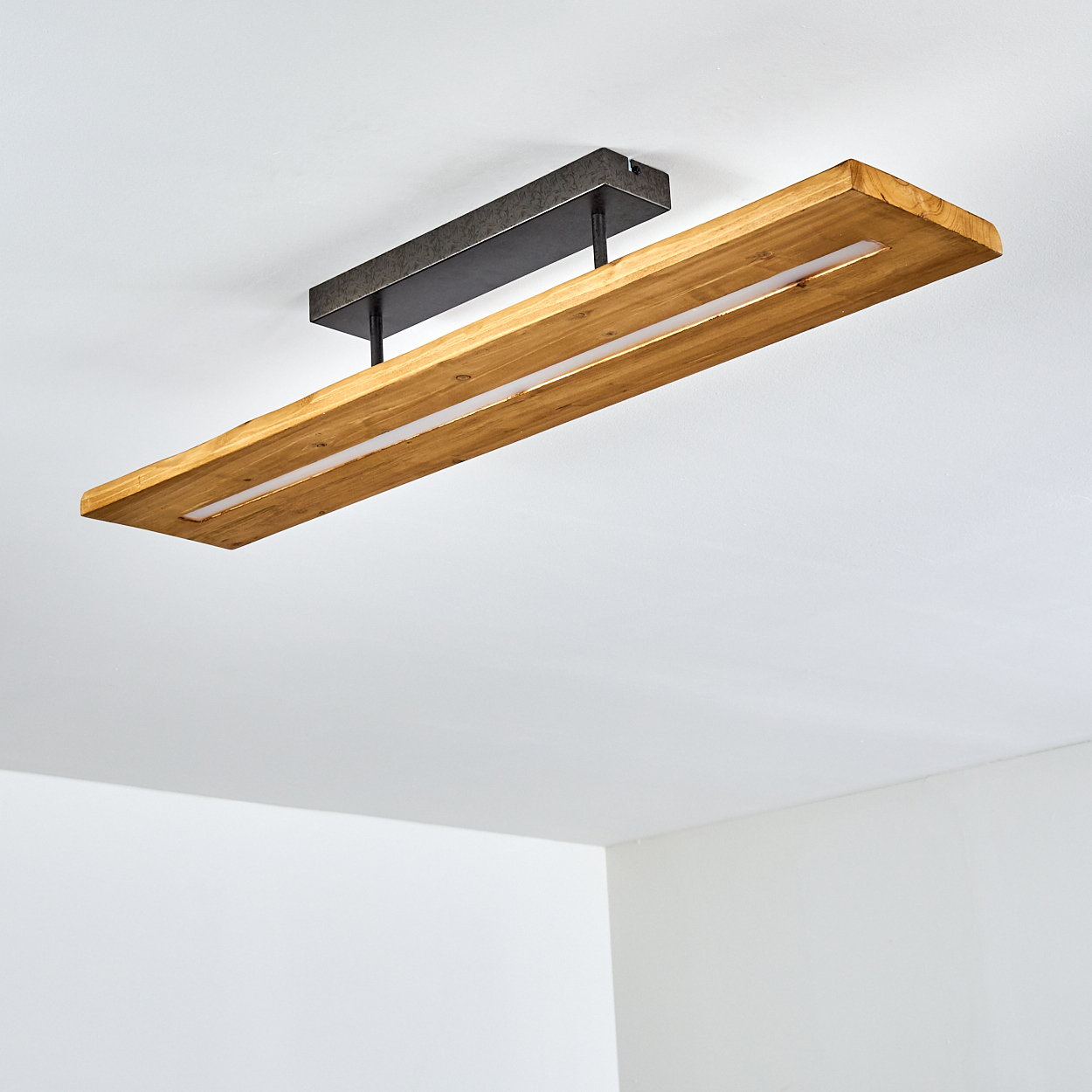 Rechteckige Deckenleuchte aus Holz mit Lichtleiste, an weißer Decke montiert. Einfaches Design.