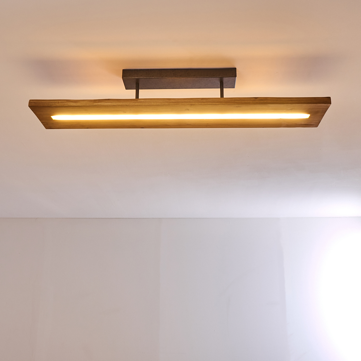 Rechteckige Deckenleuchte mit Holzsockel und linearer Lichtquelle darunter.