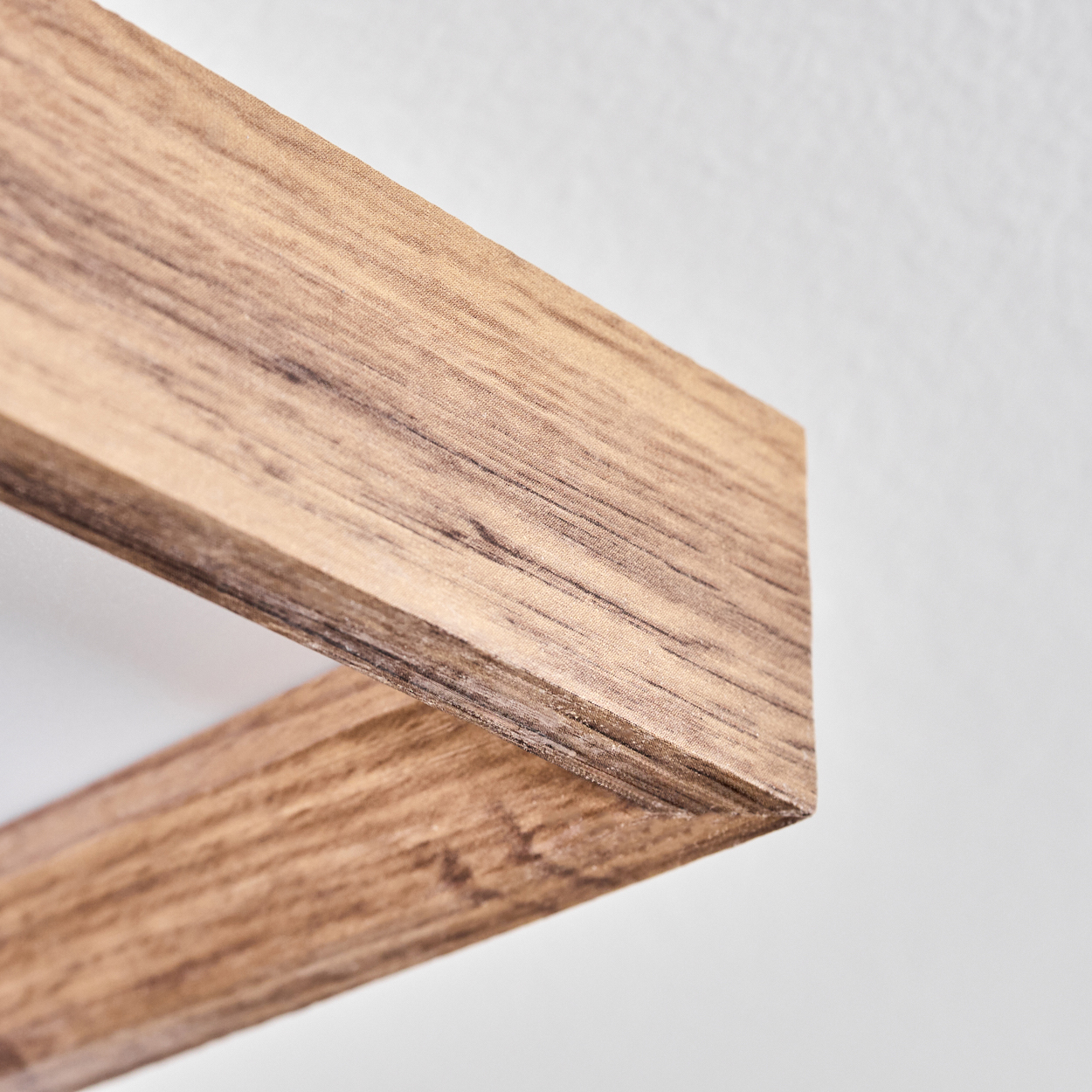 Nahaufnahme einer Ecke eines Holzrahmens, deutliche Holzmaserung, weißer Hintergrund.