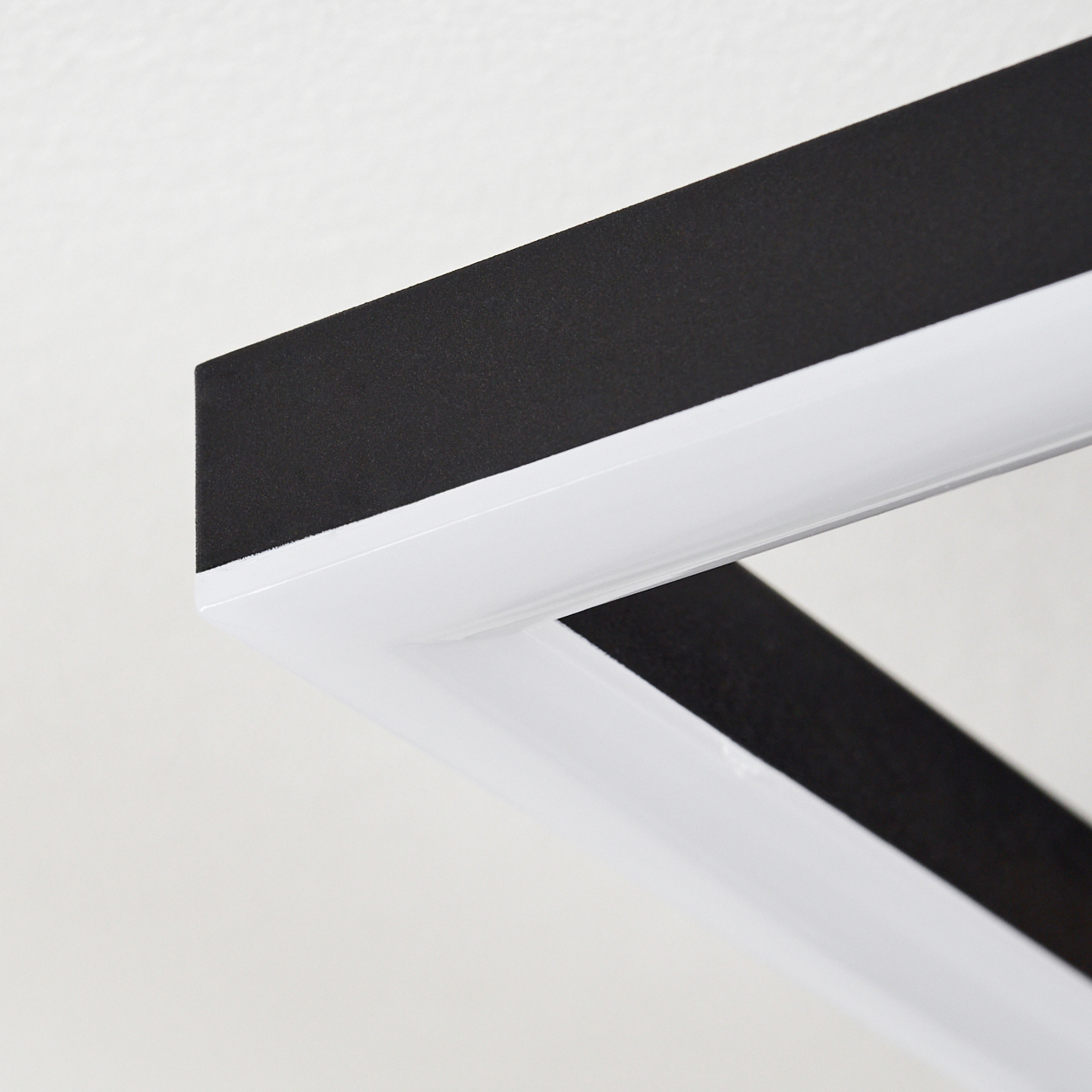 Nahaufnahme des Lichtrahmens einer modernen Deckenlampe, die weiße und schwarze Elemente zeigt.