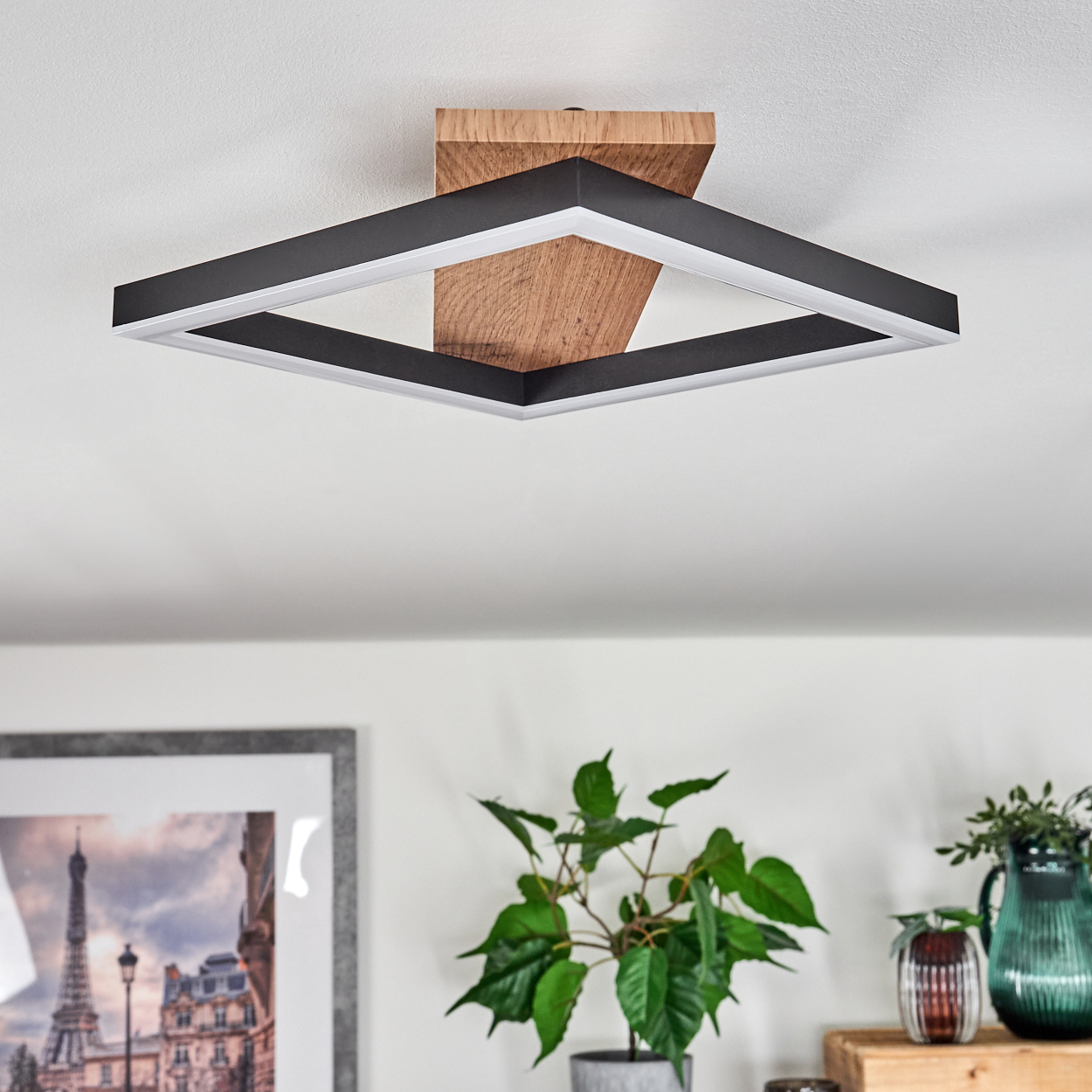 Eine quadratische Deckenlampe mit Holzbalken und quadratischem Lichtrahmen, an einer weißen Decke montiert.