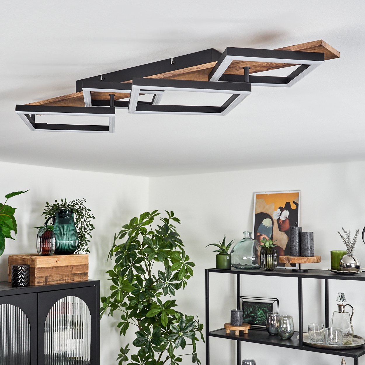 Eine moderne Deckenlampe mit Holz- und schwarzen Quadratrahmen. Der Hintergrund umfasst Möbel und Pflanzen.