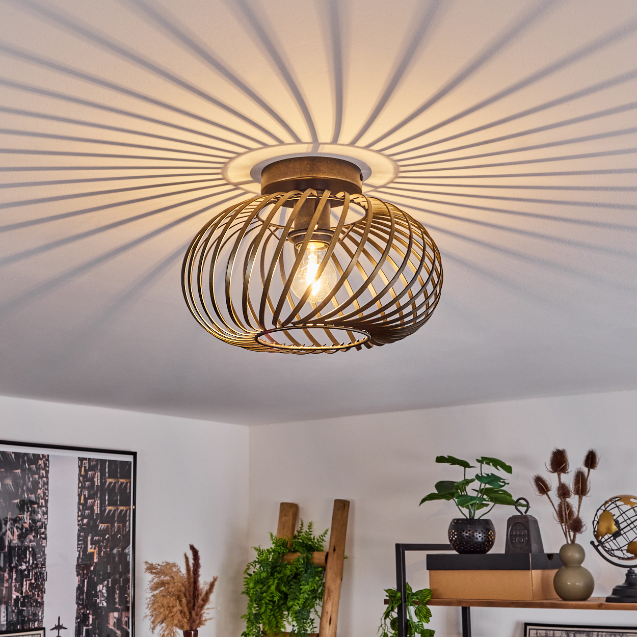 Deckenleuchte mit spiralförmigem Metalldesign, sichtbarer Glühbirne, Schatten. Pflanzen und Deko im Raum.