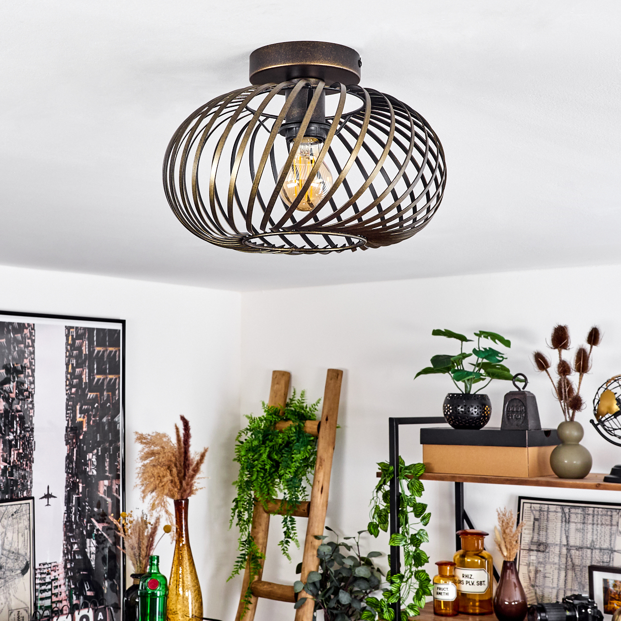Deckenleuchte mit spiralförmigem Metalldesign, sichtbarer Glühbirne, Pflanzen und Dekoration im Raum.