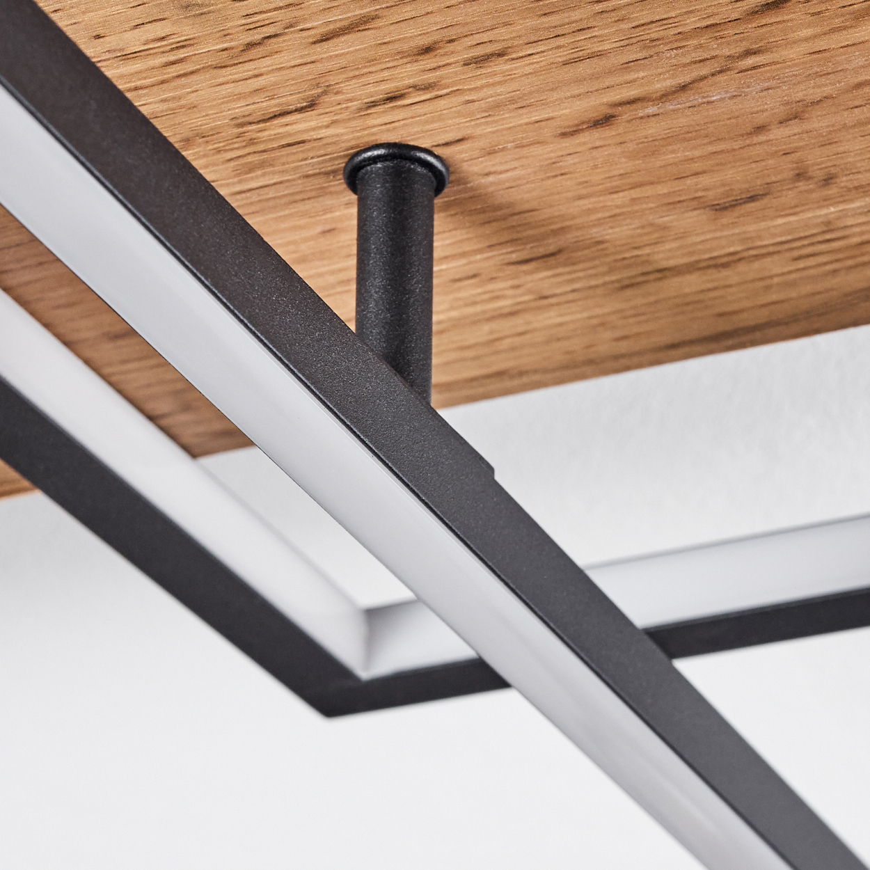 Nahaufnahme einer modernen Deckenleuchte. Schwarzer Metallrahmen mit Holzpaneel und weißem Licht.