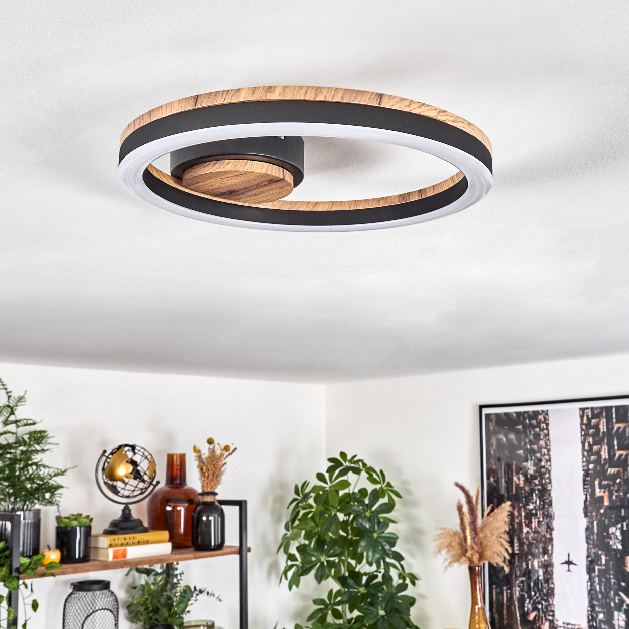 Kreisförmige Deckenleuchte mit Holz- und schwarzen Akzenten. Weißer Lichtring. Hintergrund: weiße Decke, Deko.