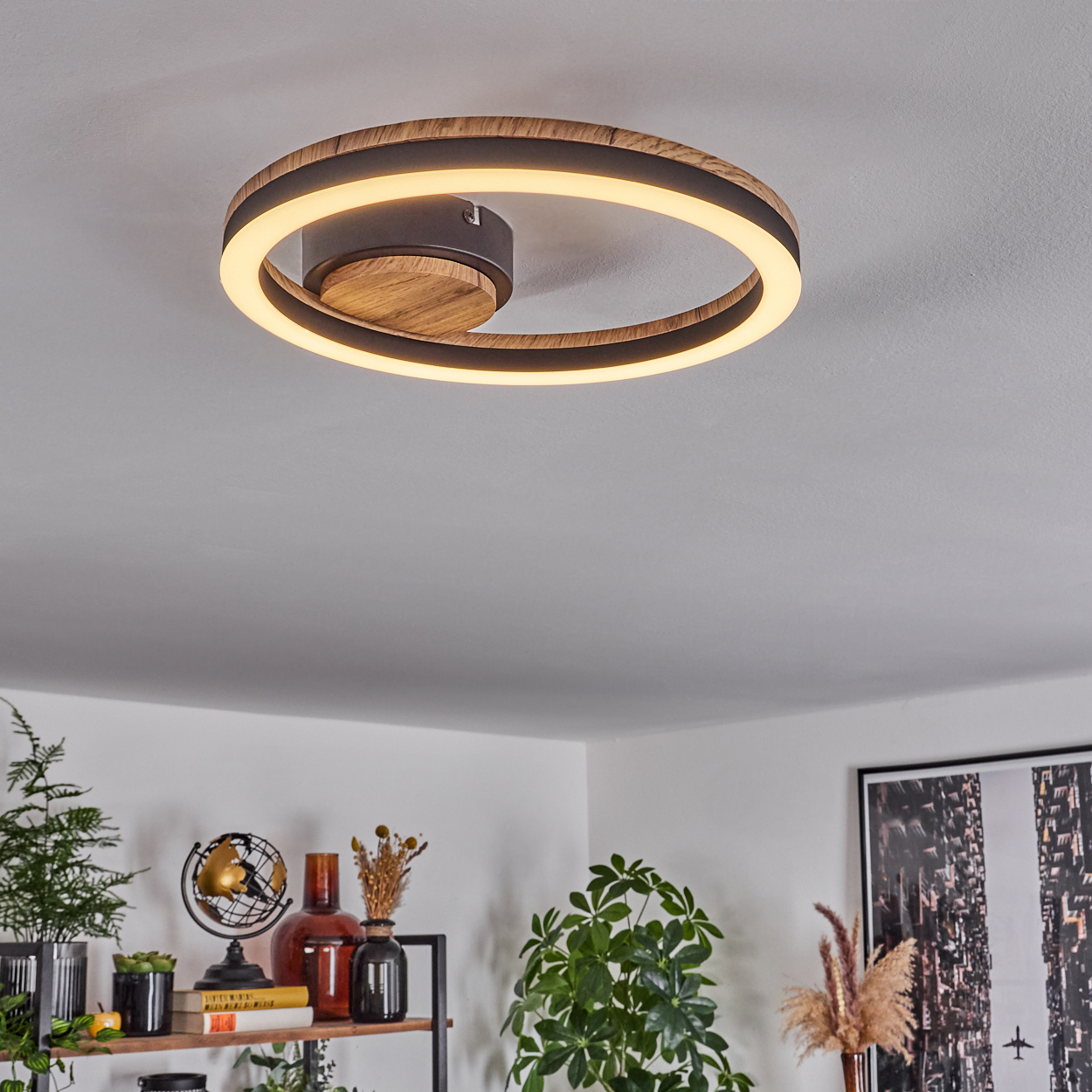 Kreisförmige Deckenleuchte mit Holz- und schwarzen Akzenten. Weißer Lichtring. Hintergrund: weiße Decke, Deko.