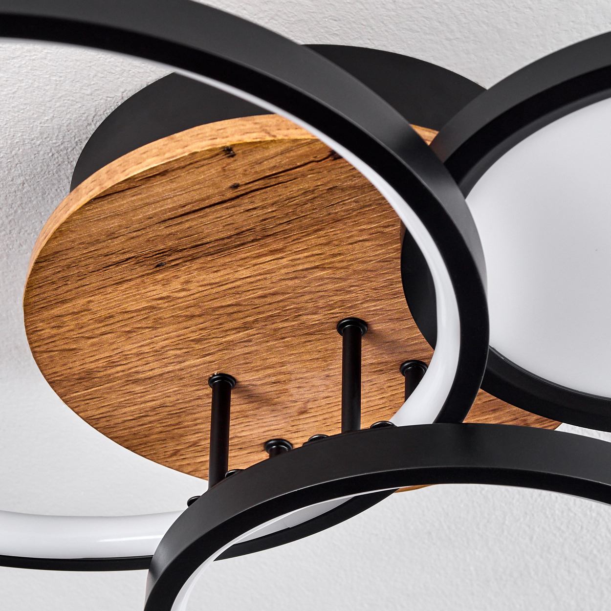 Nahaufnahme einer Deckenleuchte mit Holz- und Schwarzelementen. Der Hintergrund ist weiß.