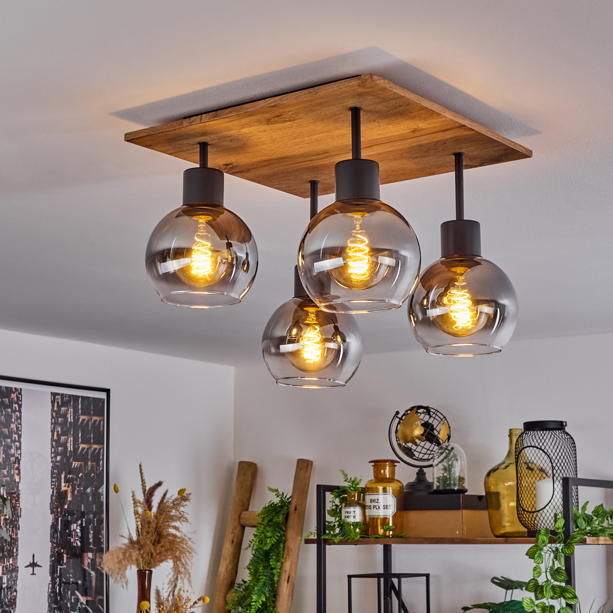 Eine Deckenlampe mit vier Glühbirnen, vier Glaskugeln, mit Raumdekor im Hintergrund.