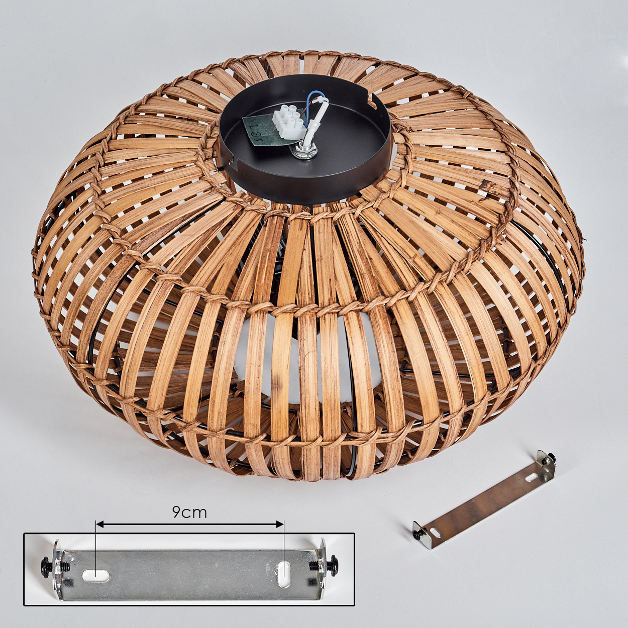Eine Rattanlampe mit schwarzem Sockel und einer Metallhalterung auf weißer Oberfläche.