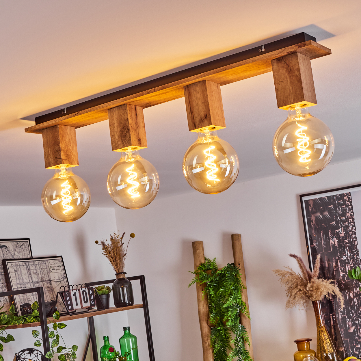 Deckenlampe mit vier Globuslampen, Holzbalken. Der Hintergrund zeigt Dekor, darunter Bilder und Pflanzen.