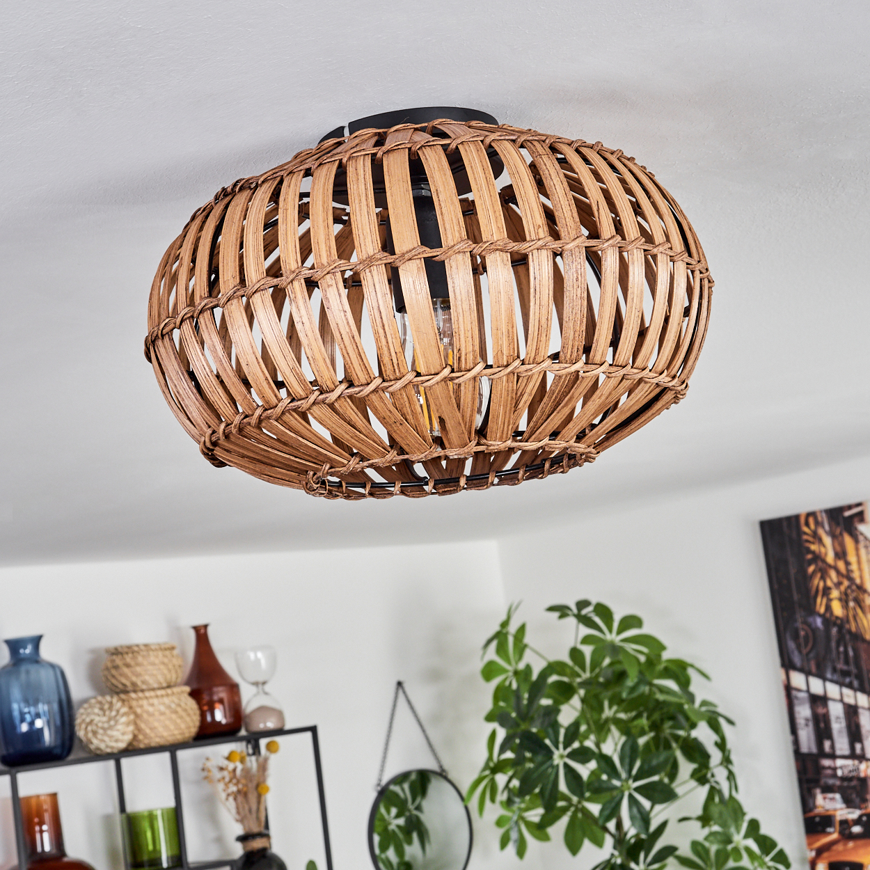Eine Deckenlampe aus geflochtenem Rattan mit schwarzem Sockel vor einer weißen Decke.