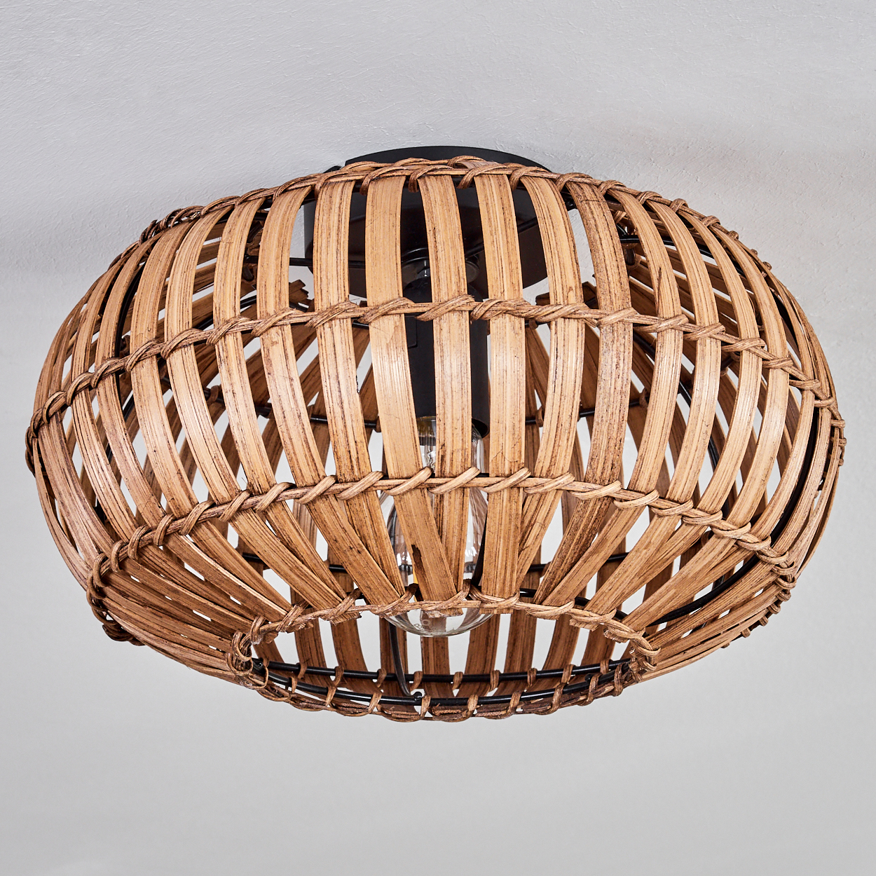 Geflochtene Deckenlampe aus Rattan mit einer Glühbirne. Die Lampe ist rund.