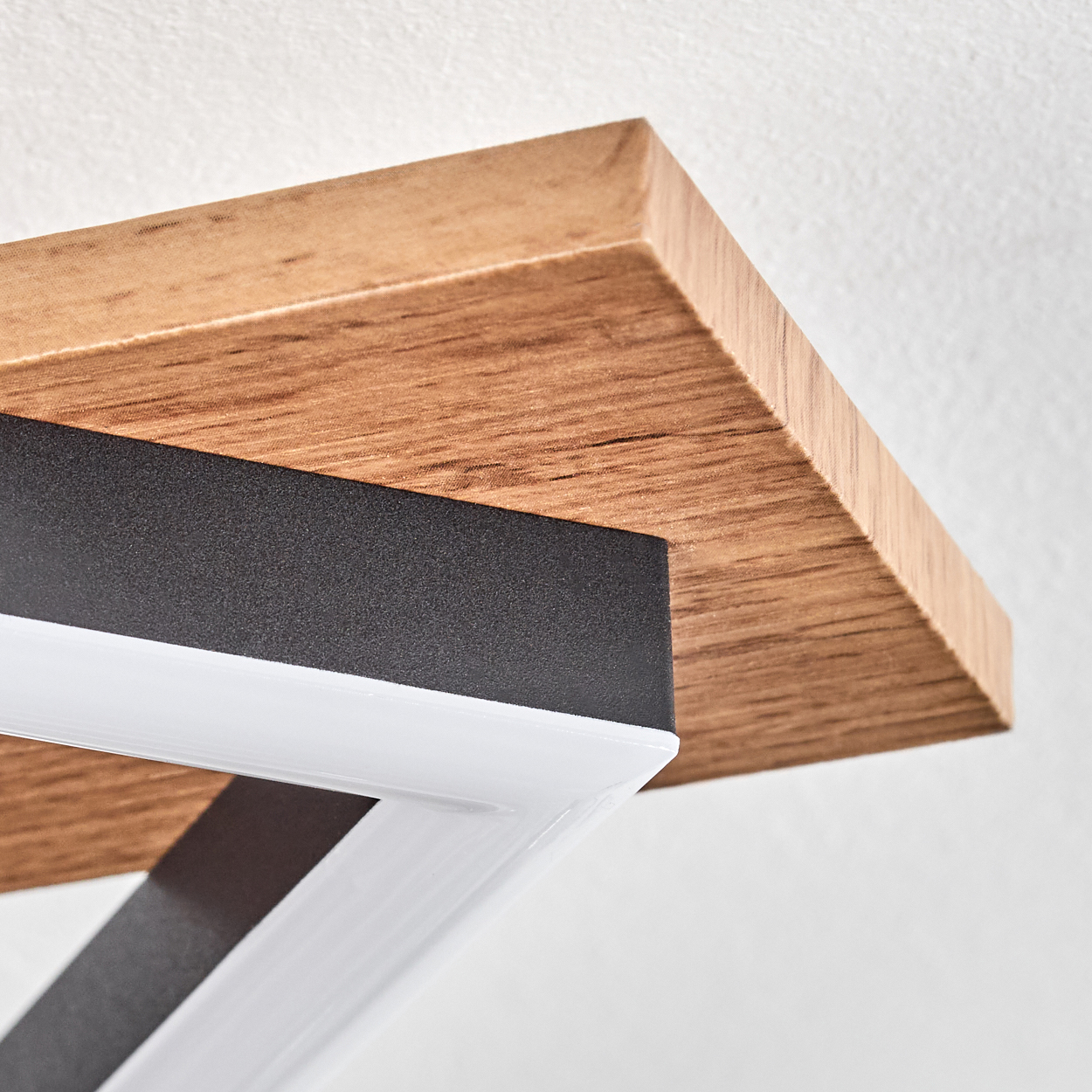 Nahaufnahme eines Holzregals mit einem schwarz-weißen Metallrahmen. Das Regal ist auf einer weißen Oberfläche montiert.